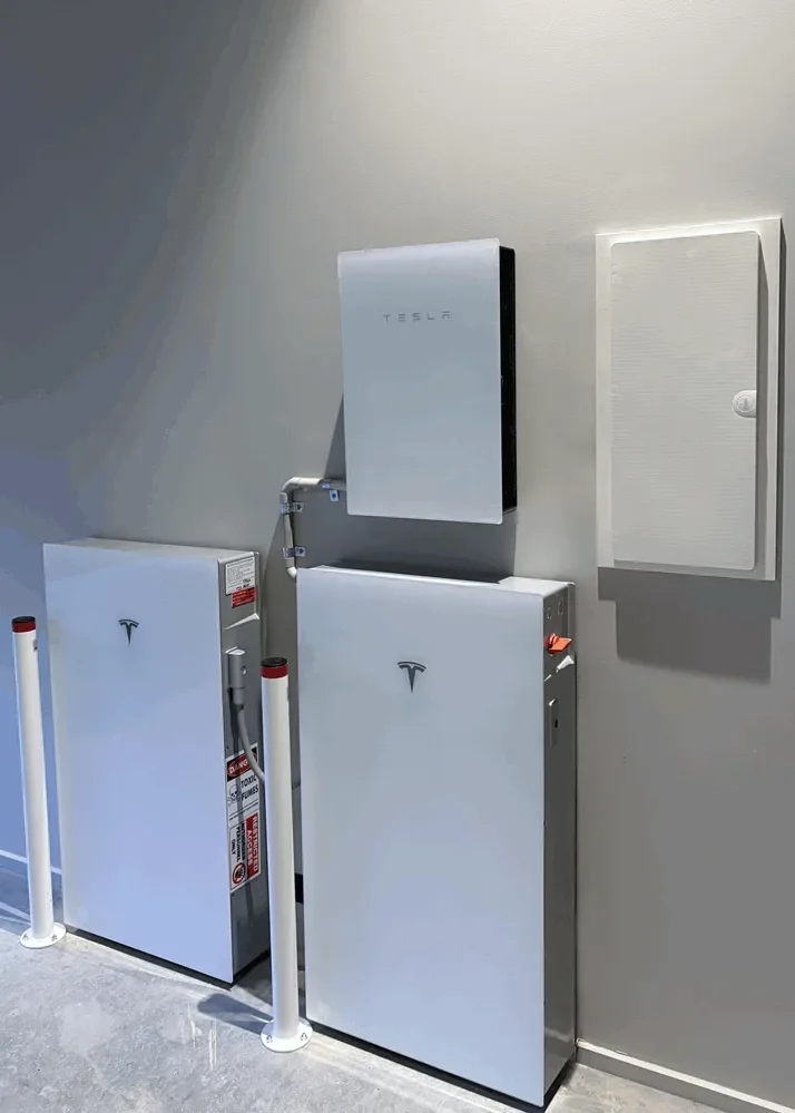 Electrical equipment and a wall-mounted box with Tesla branding inside a building.