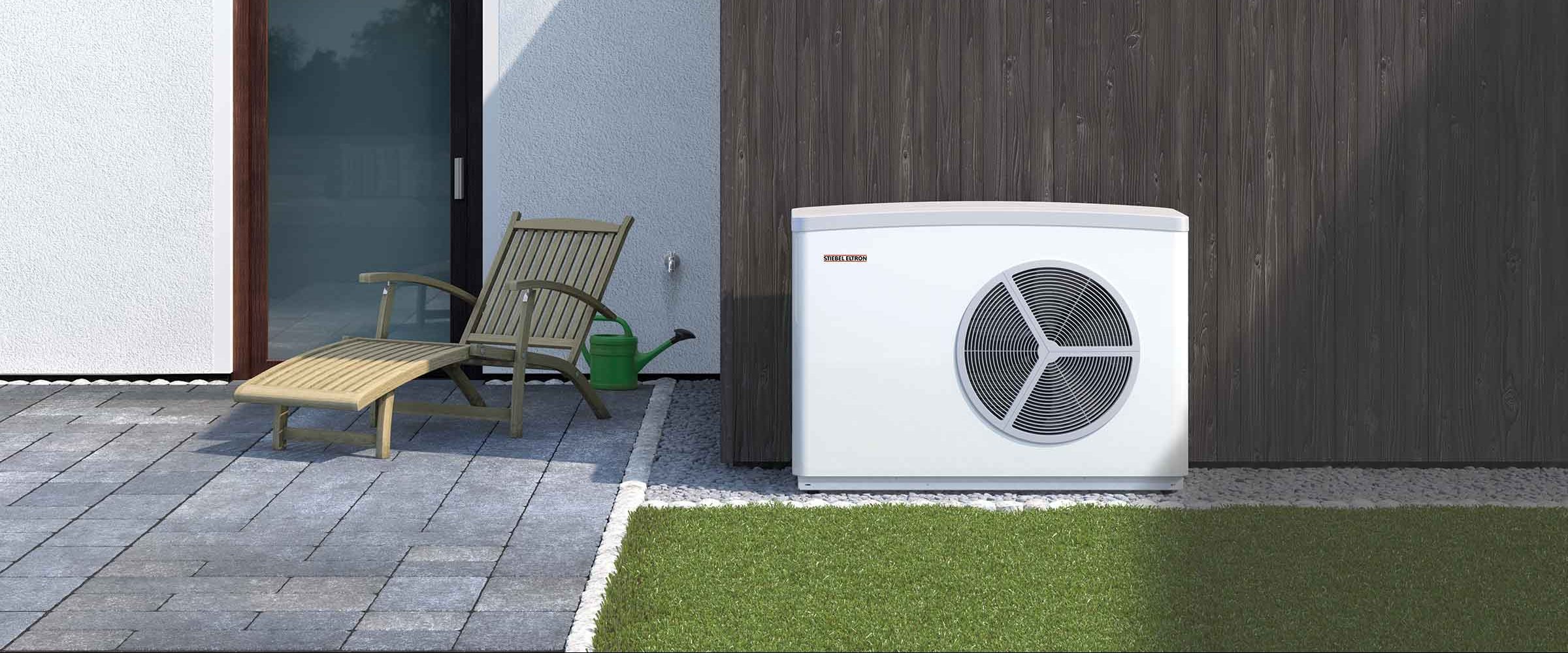 Exterior of a modern house with a sliding glass door, wooden and light-colored textured walls, a deck chair with a green watering can next to it, and a large outdoor air conditioning unit against the wall.
