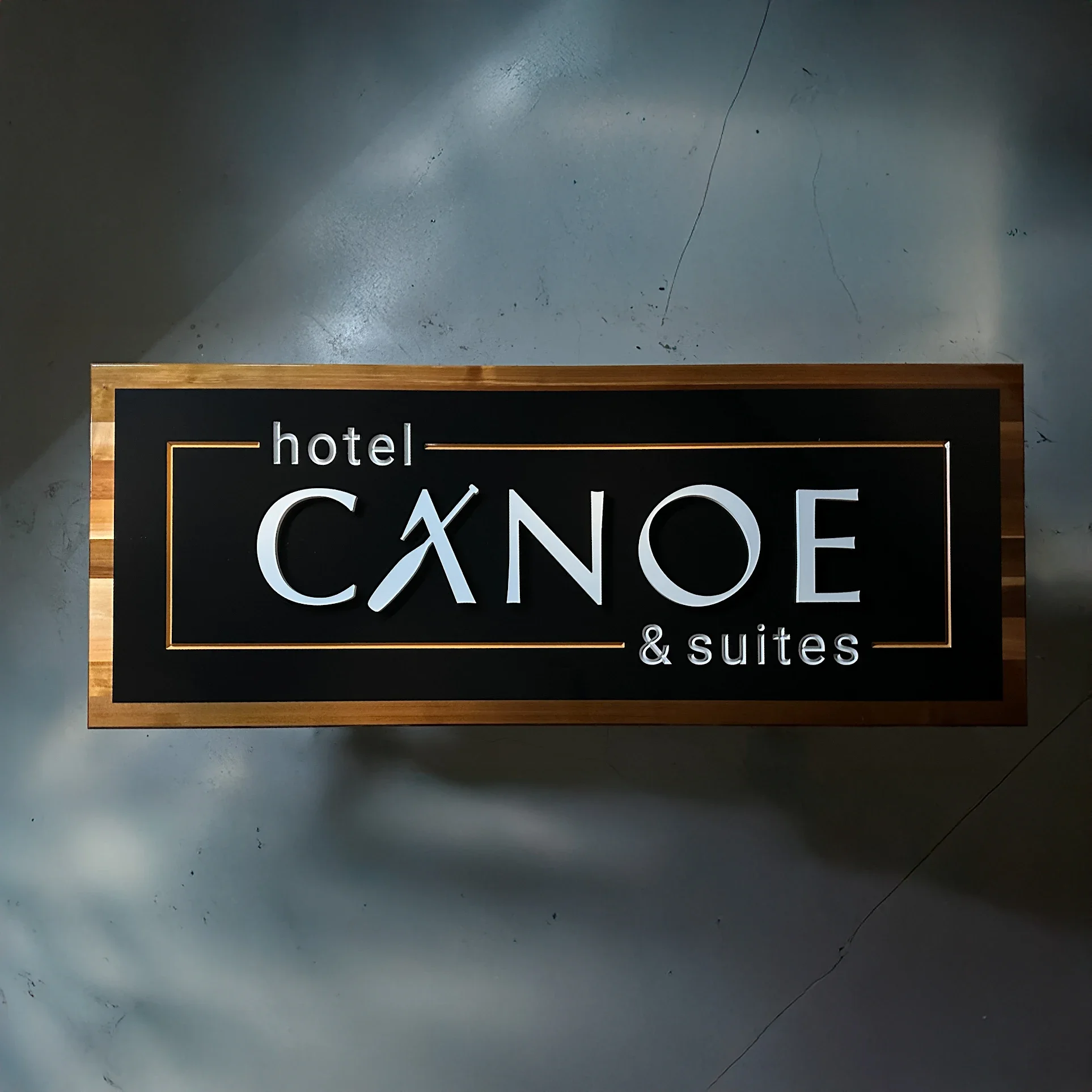 Black and gold Hotel Canoa & Suites sign mounted on a concrete wall