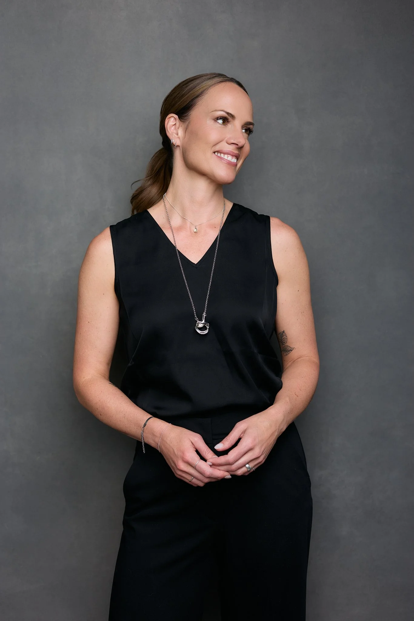 Professional studio portrait of a Jaime Birch wearing a black sleeveless outfit against a grey background.