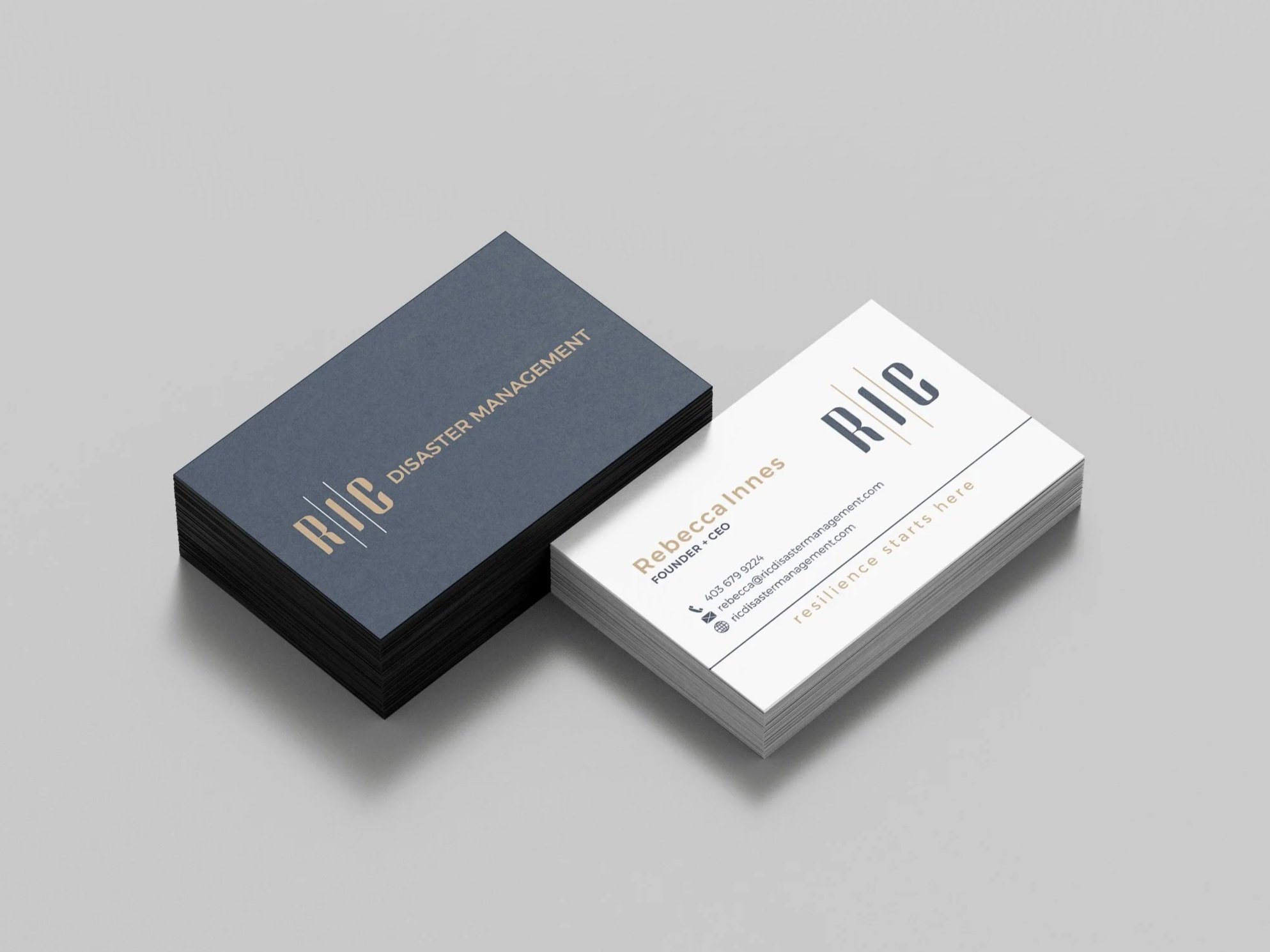 Stacks of dark and white business cards for RIC Disaster Management on a gray background