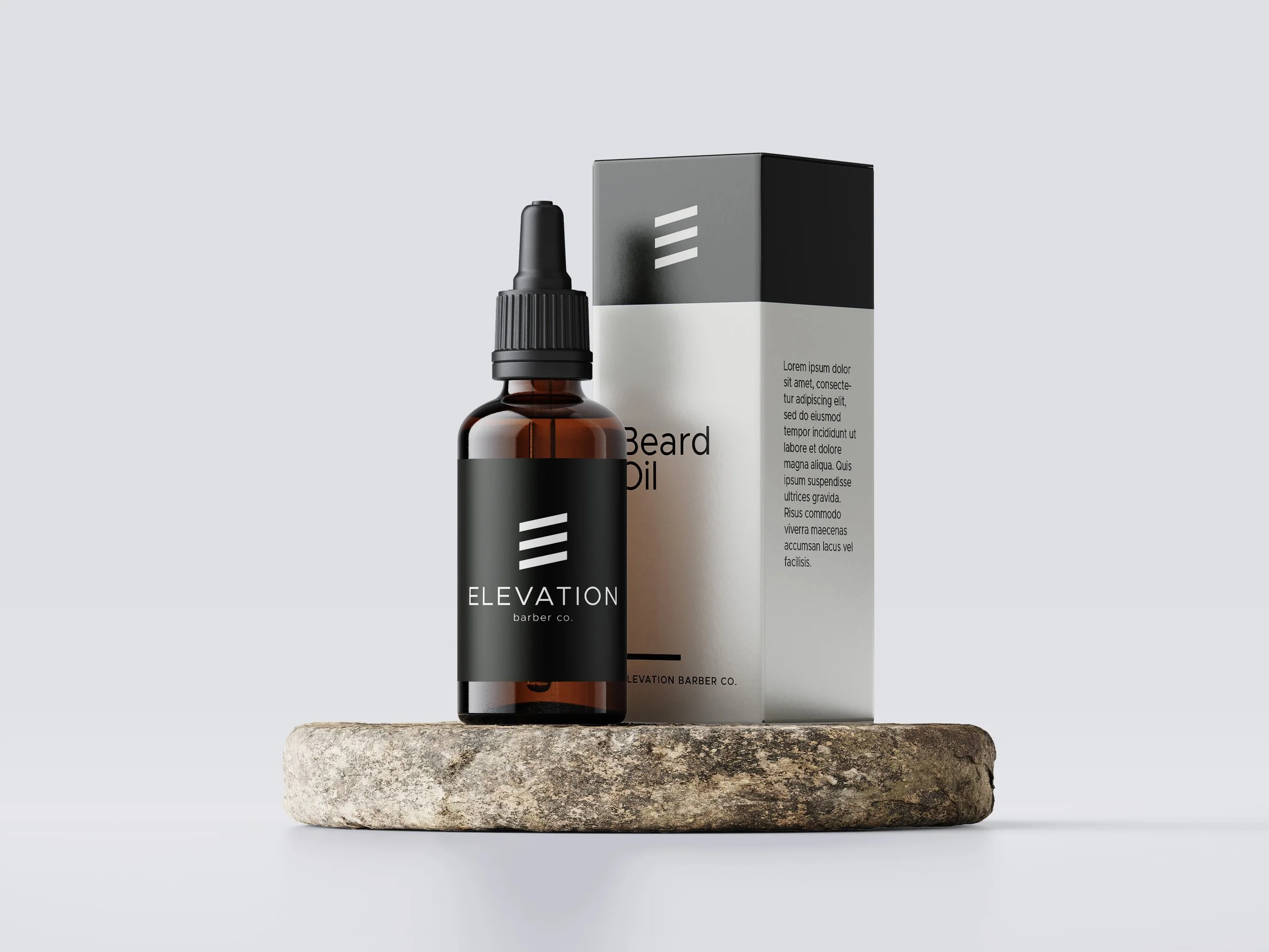 Amber dropper bottle of Elevation Barber Co. beard oil beside its black-and-white product box on a stone surface