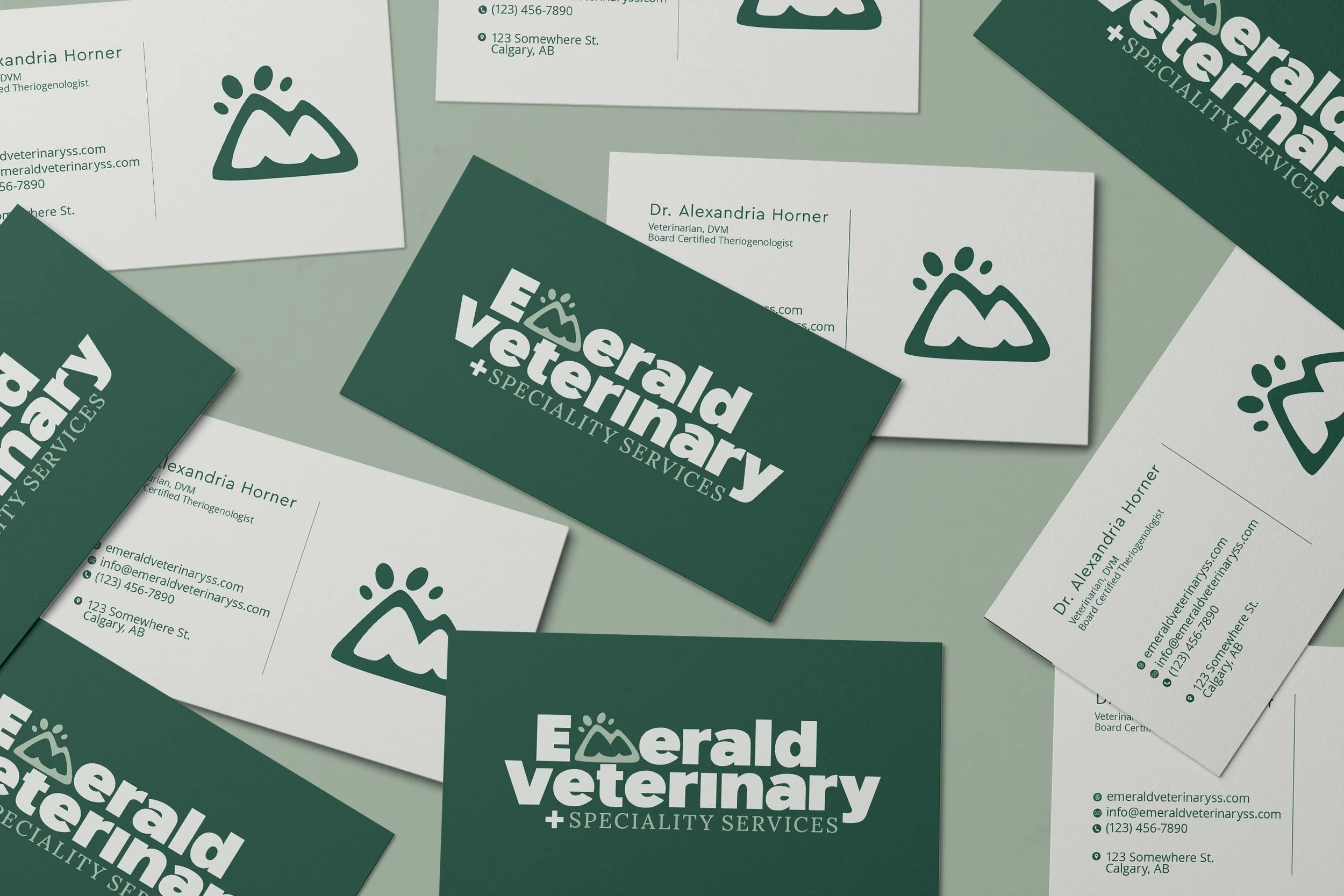 Emerald Veterinary specialty services business cards featuring a paw-print mountain logo and veterinarian contact information