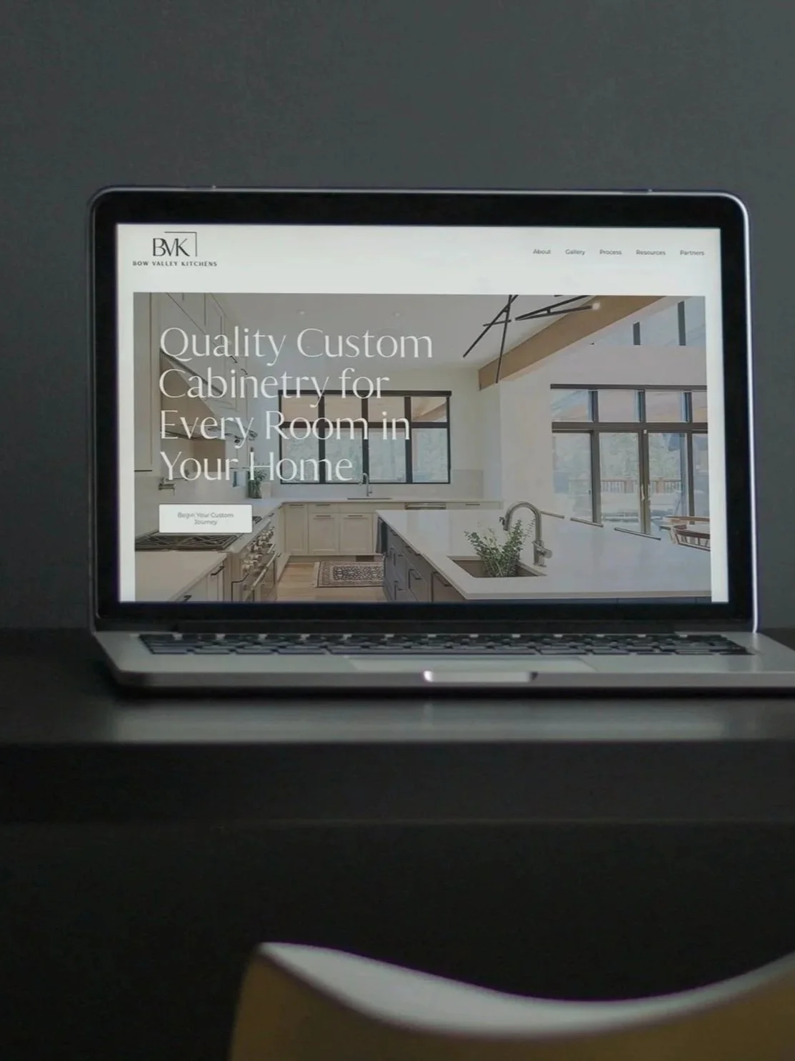 Laptop displaying the Bow Valley Kitchens website with a modern custom kitchen cabinetry interior