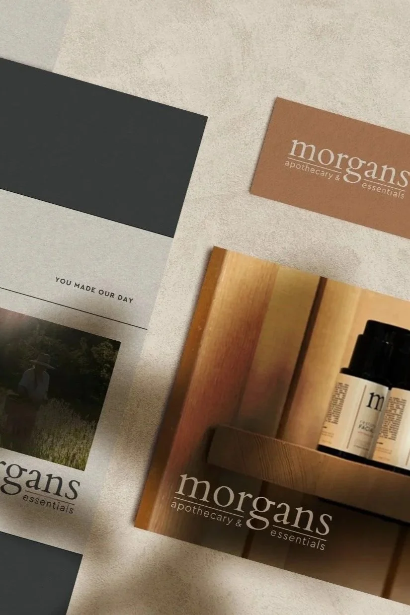 Flat lay of Morgans Apothecary & Essentials branding materials, including brochures, product packaging, a thank-you card, and a black business card.