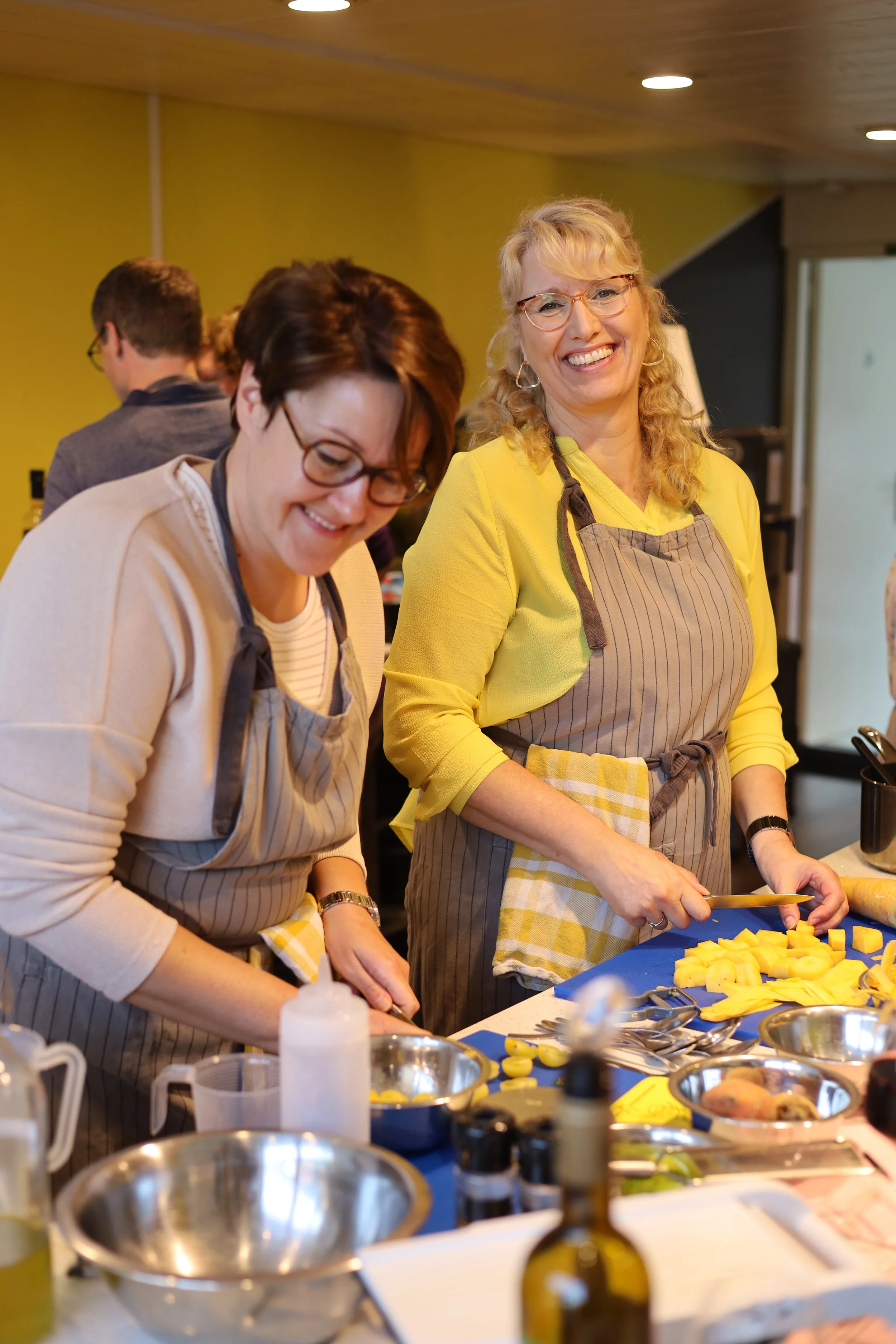 Mensen die in een keuken recepten voorbereiden, gehakt en andere ingrediënten snijden, met bakplaten en keukenbenodigdheden op de tafel.