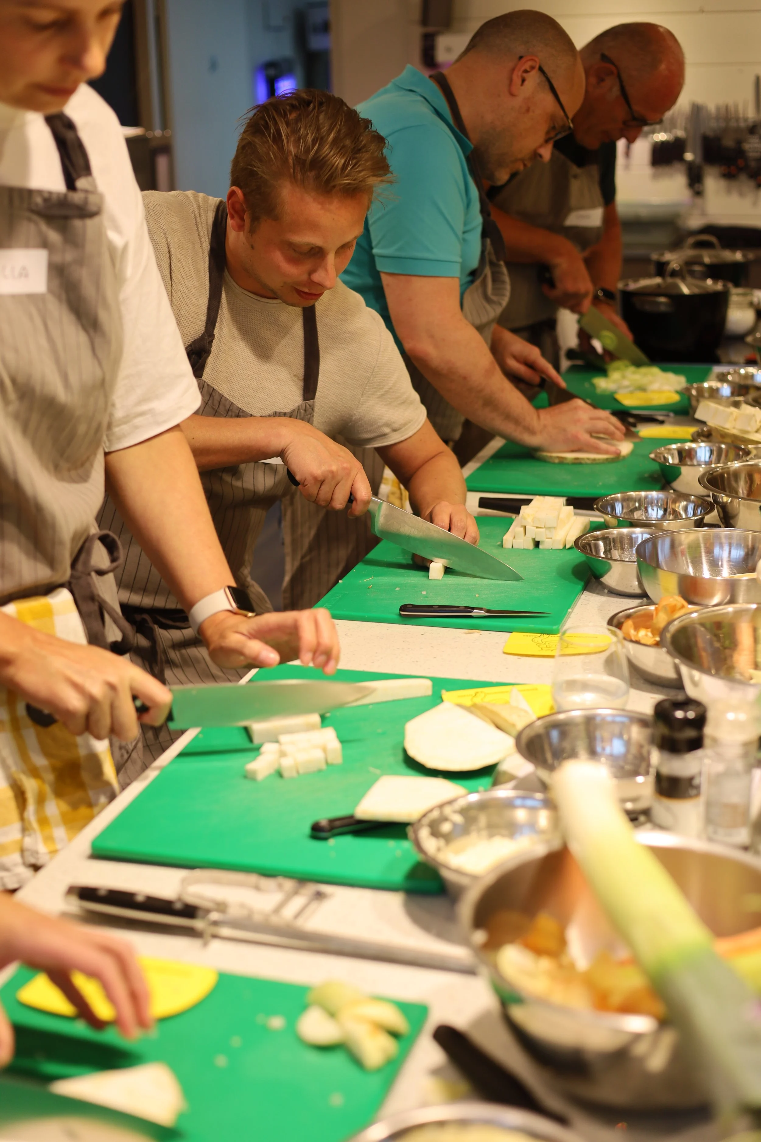 Mensen die op een groene snijplank groenten en ingrediënten snijden in een keuken.