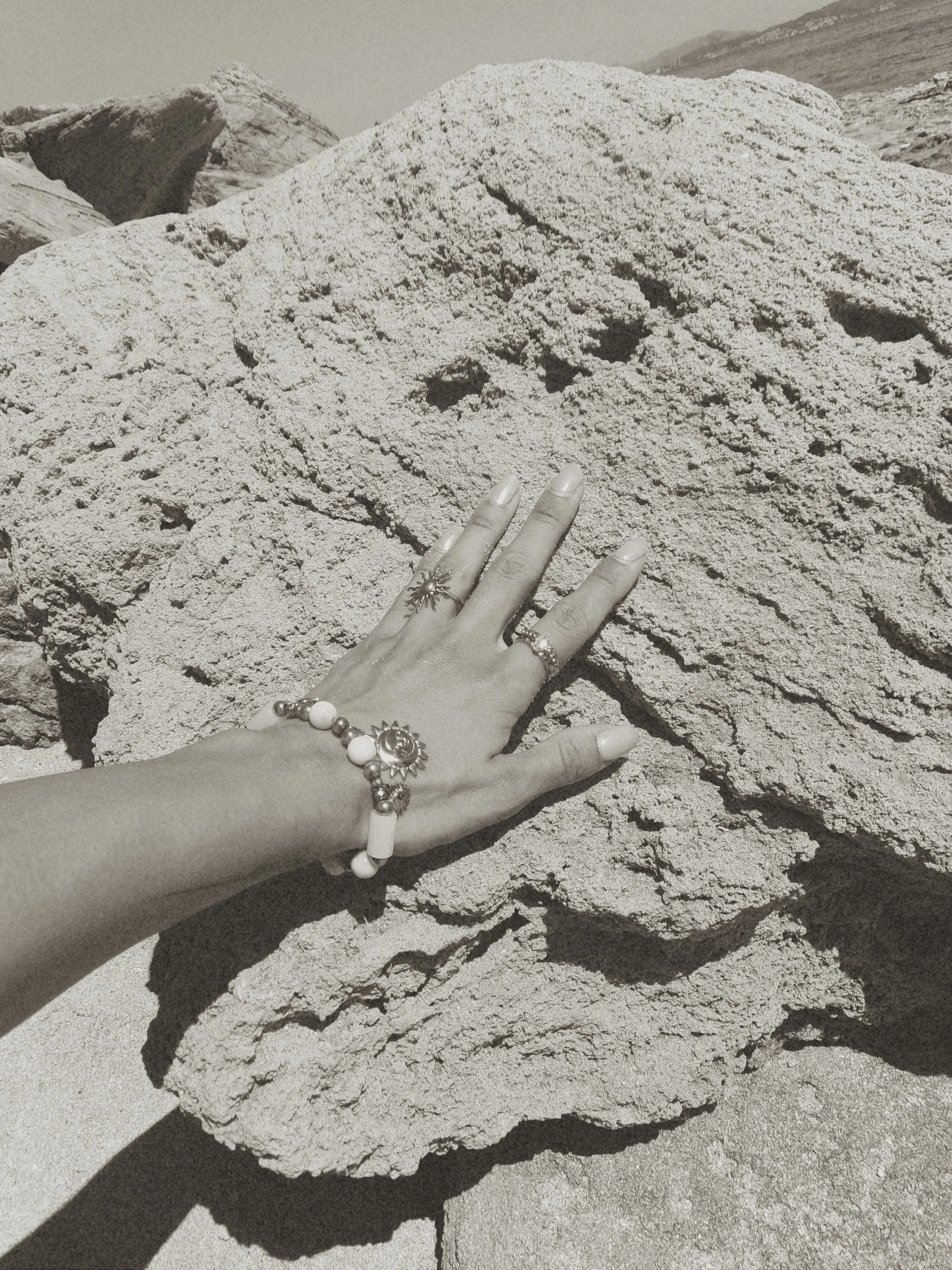 Hand resting against sun-warmed coastal rock in the Mediterranean