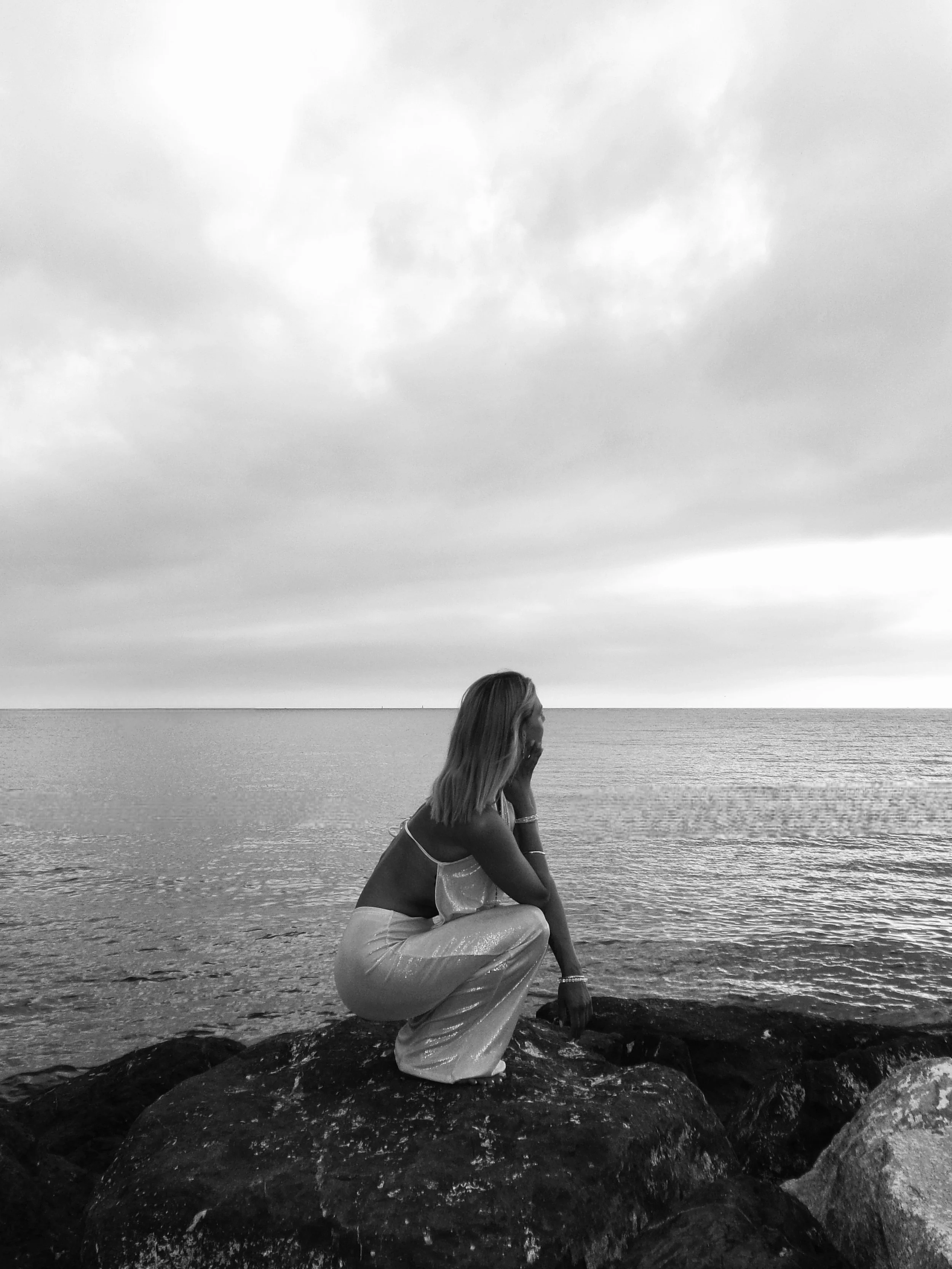 Photograph of a woman on a rock, cloudy sky