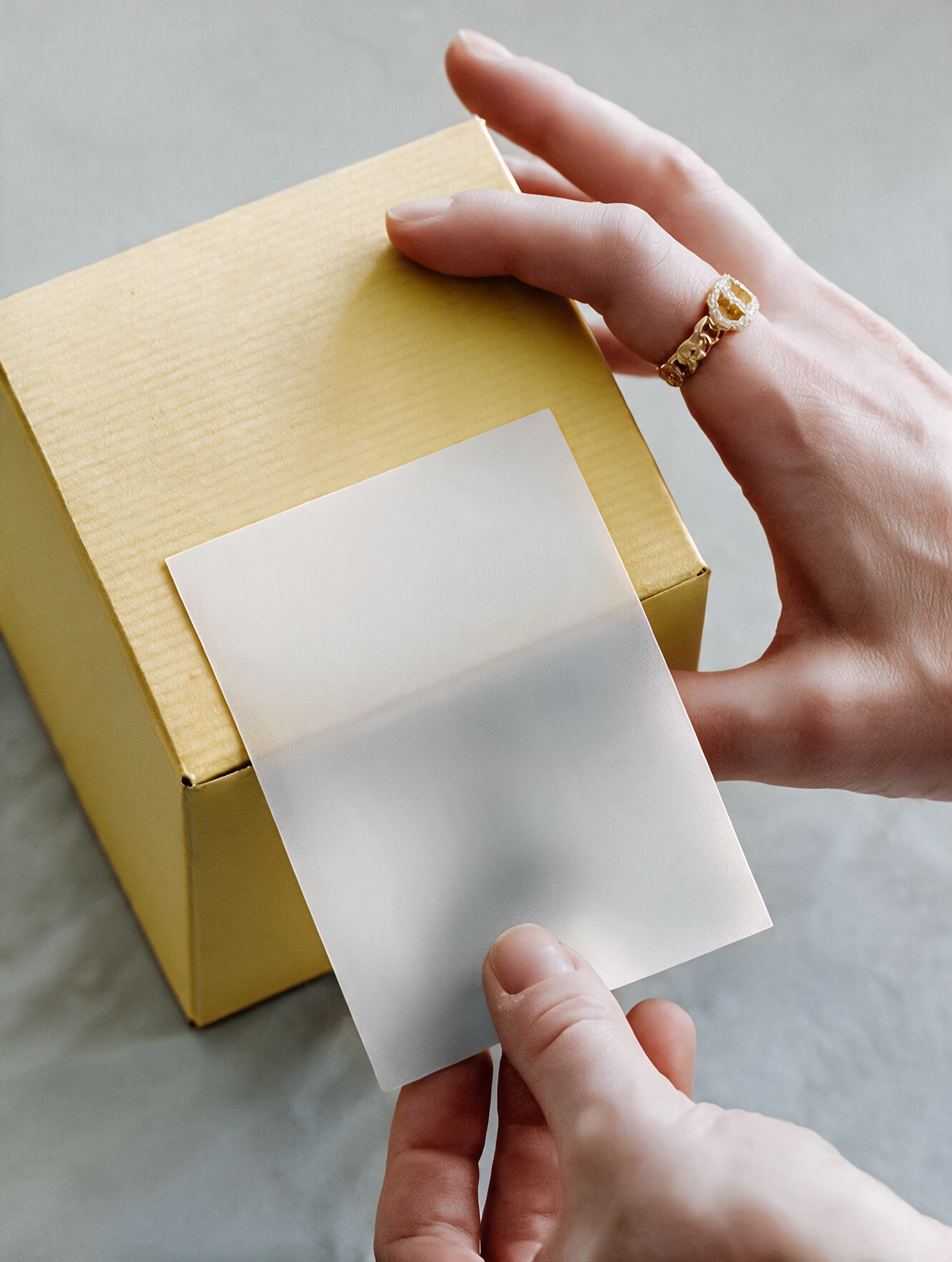 A person's hand is peeling a white sticker from a piece of white paper, with a yellow box in the background.