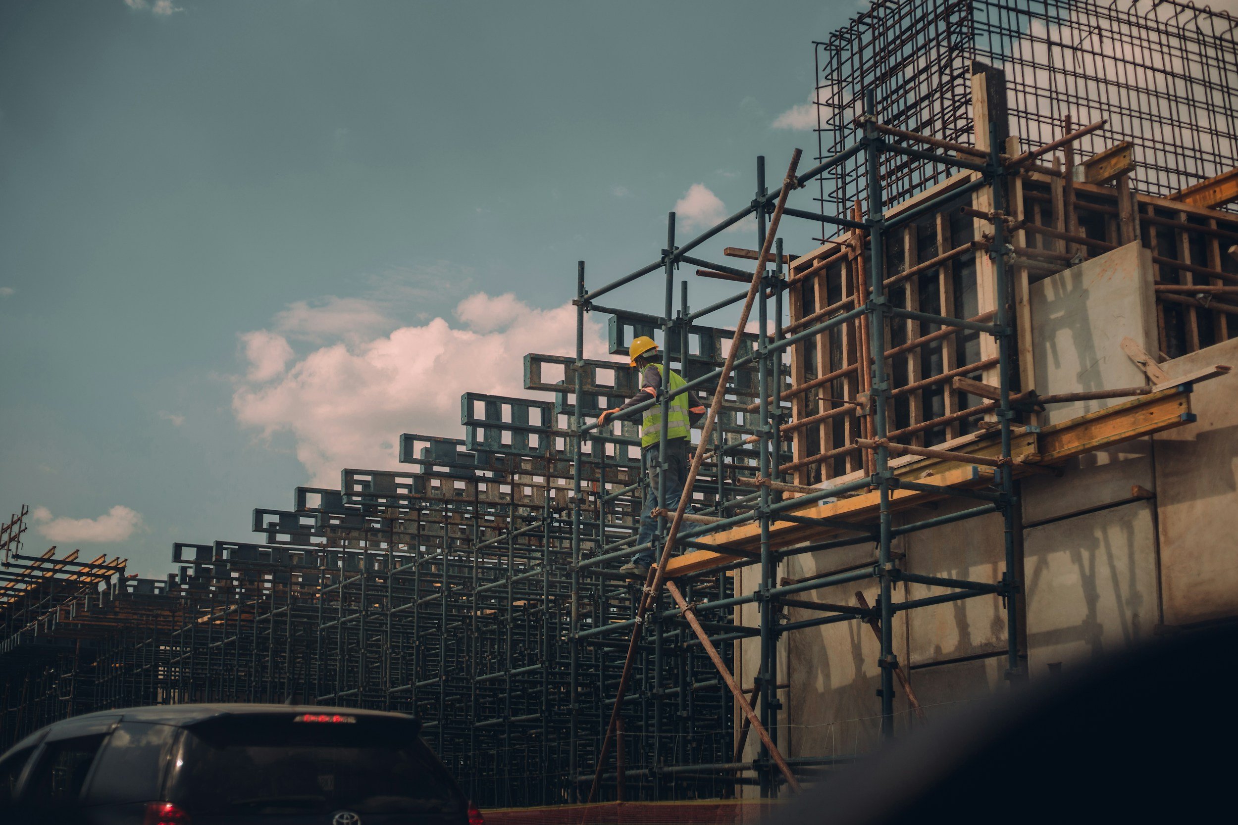 Construção de edifício com estrutura de aço e trabalhadores usando capacete na obra.