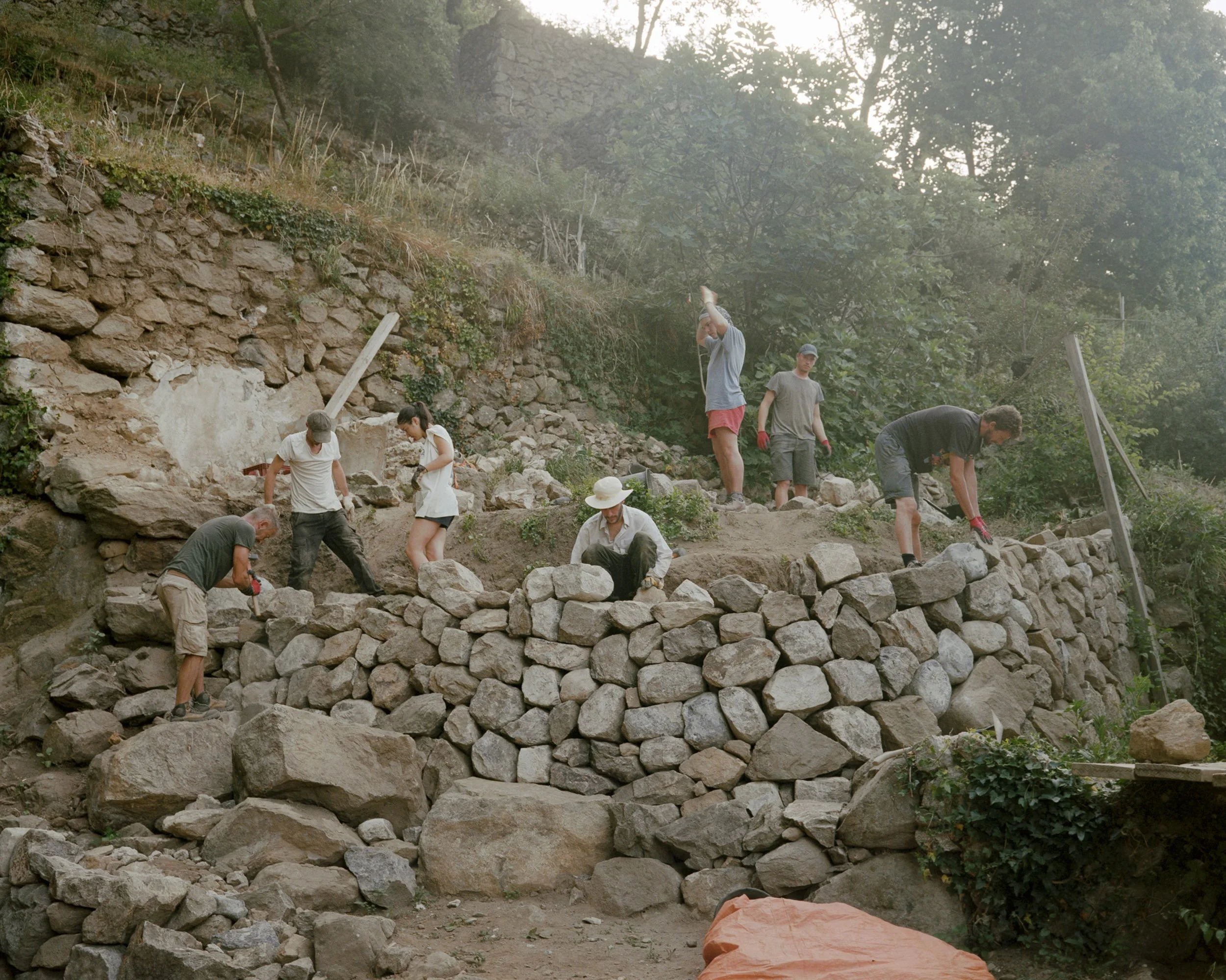 Chantier participatif pour la construction de murs en pierre sèche pour réparer ceux encadrant le torrent qui passe par le moulinage.