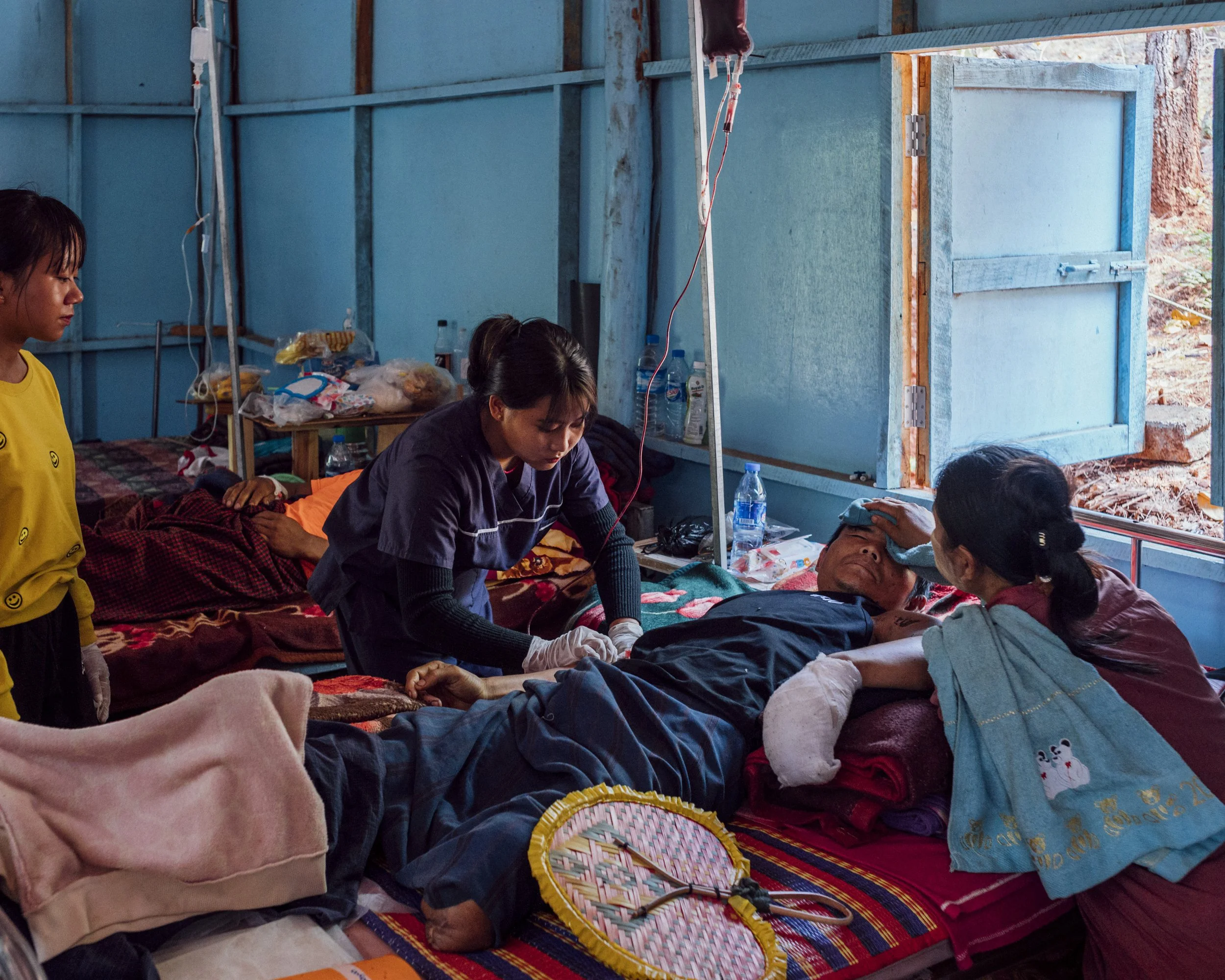 Patrick (lying down) receives treatment in a room at O1 Hospital, a medical clinic hidden in the outskirts of Demoso, in an area controlled by the rebellion against the military junta. Already the victim of an artillery shelling that cost him his lef