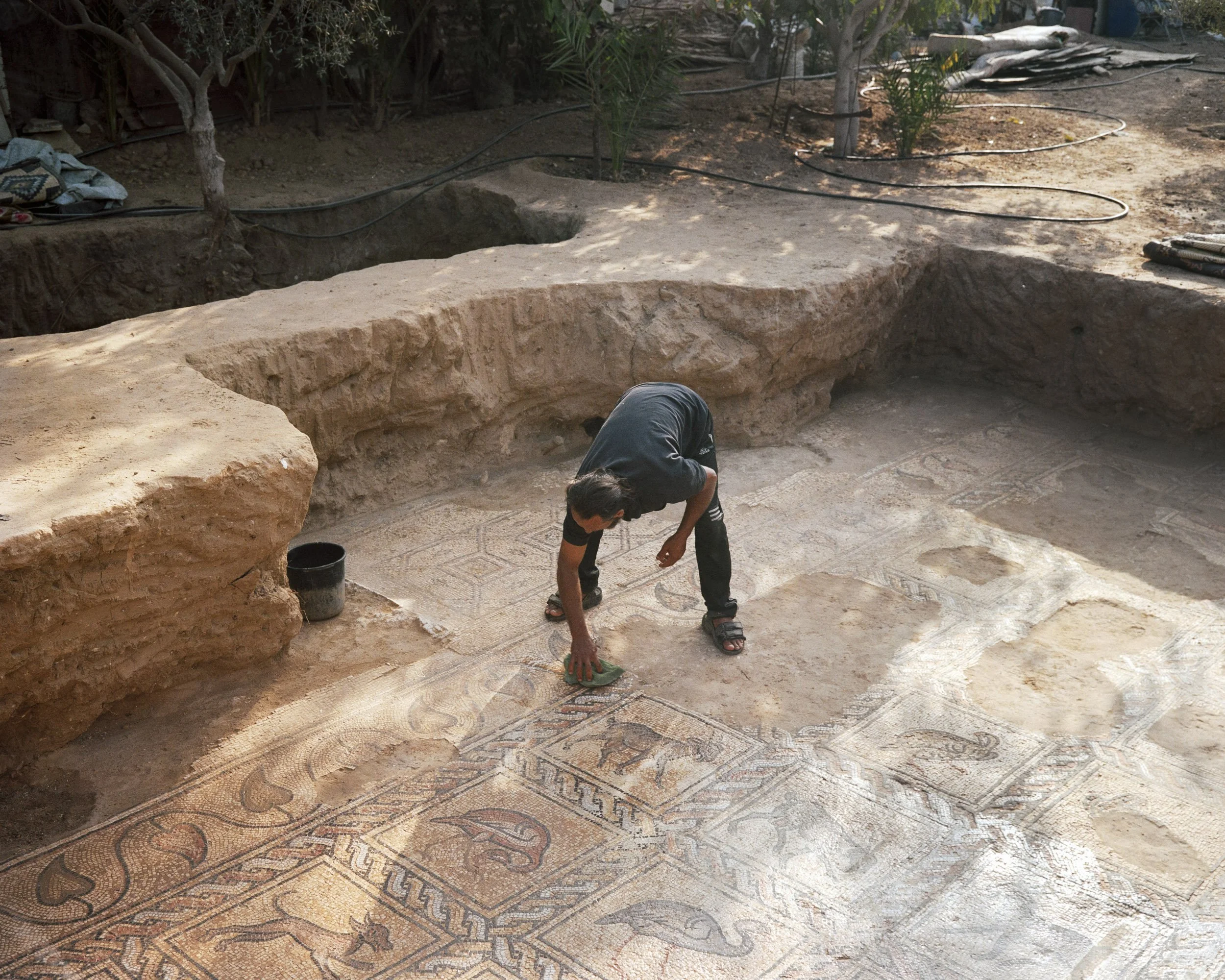 Salman al-Nabahin cleans the 5th-7th century mosaics he discovered in his garden near Bureij. Gaza Strip, October 4, 2022. © Lucien Lung / Riva-Press