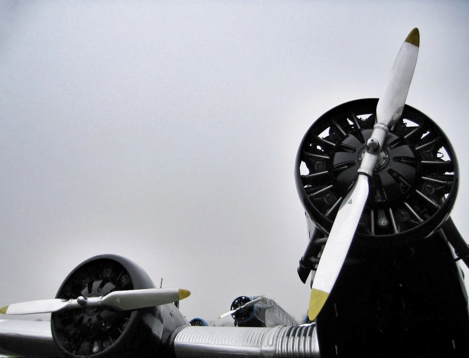 Close-up view of multiple vintage propeller airplane engines against an overcast sky.
