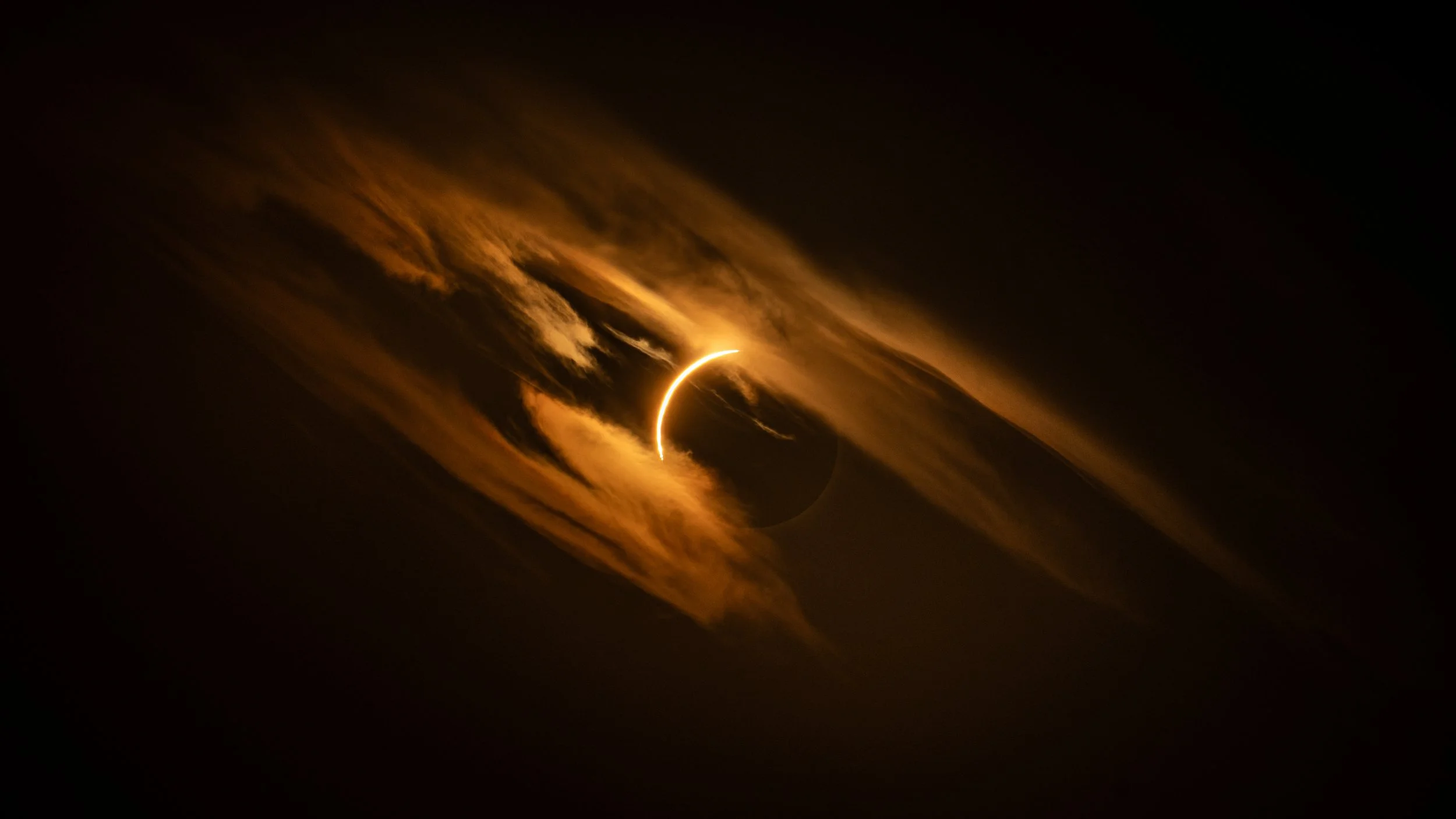 Thin crescent of sunlight at the edge of the eclipsed sun, seen through copper cloud over Ibiza, Spain, 12 August 2026