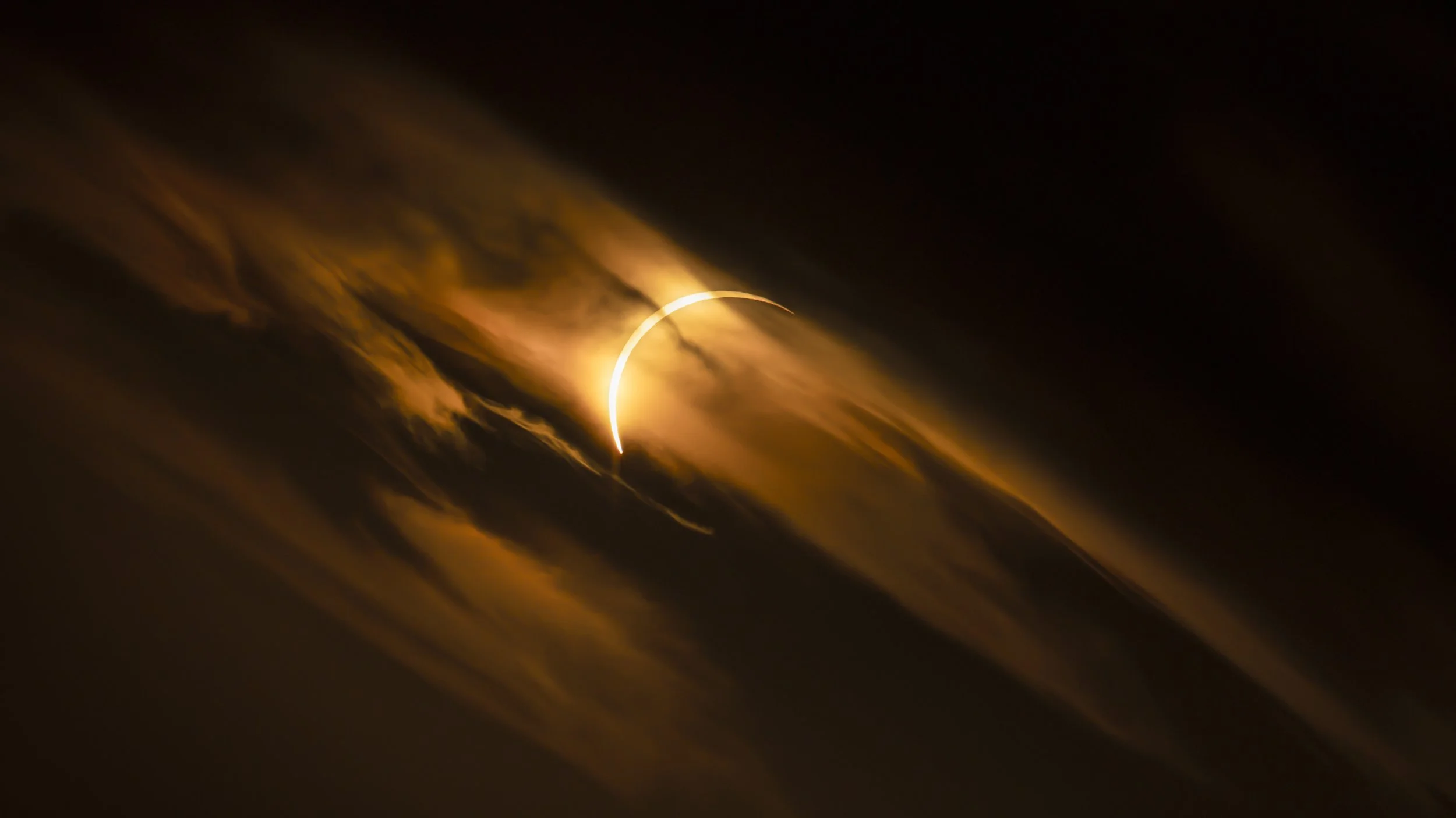 The diamond ring through broken cloud seconds before totality, Ibiza, Spain, 12 August 2026 — the sun only a few degrees above the horizon, which is why the cloud burns copper.