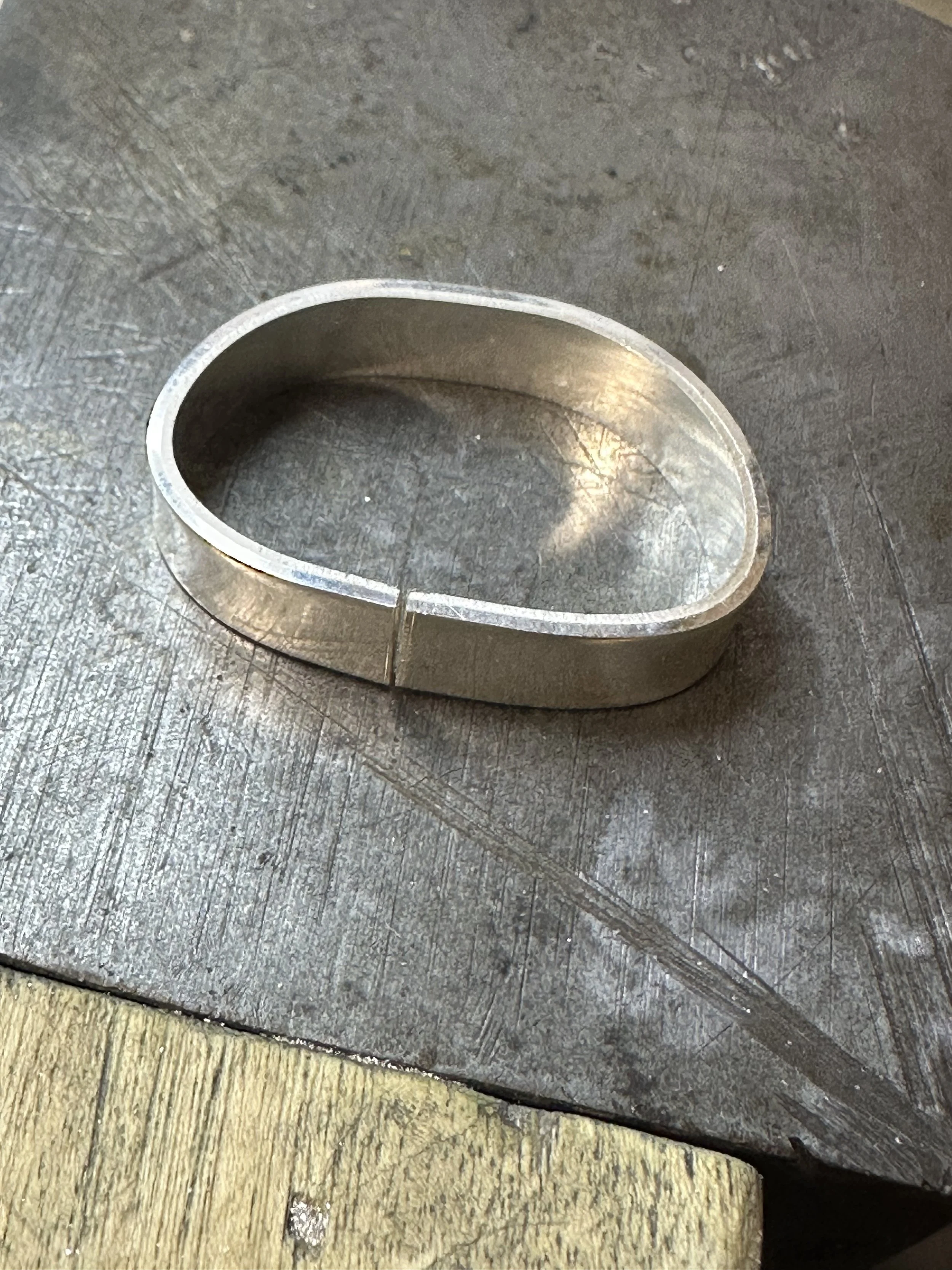 A silver ring that has been roughly formed and shows a small gap between the ends that will receive solder.