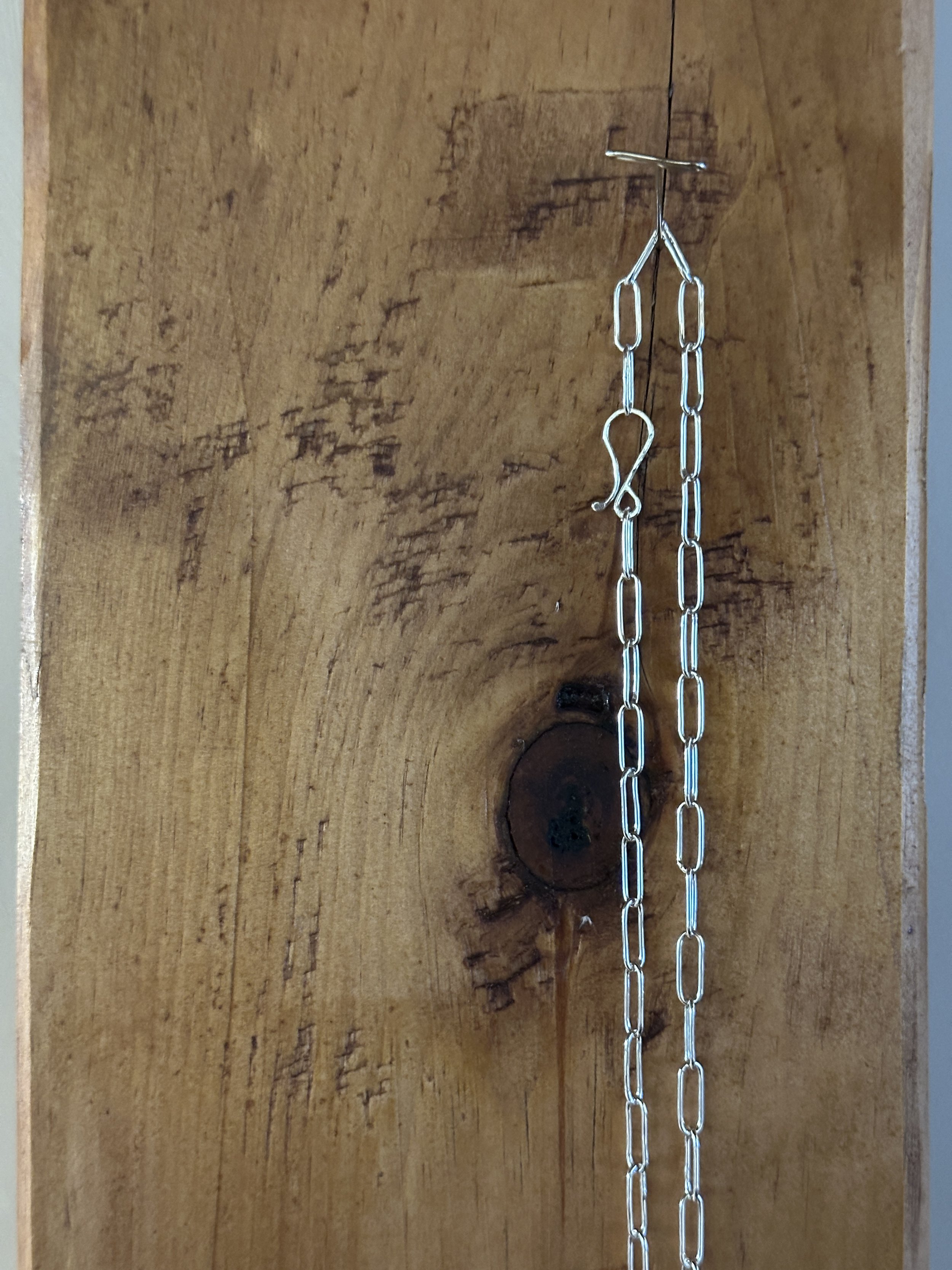 Close-up of a handmade sterling silver S-hook clasp on a paperclip chain