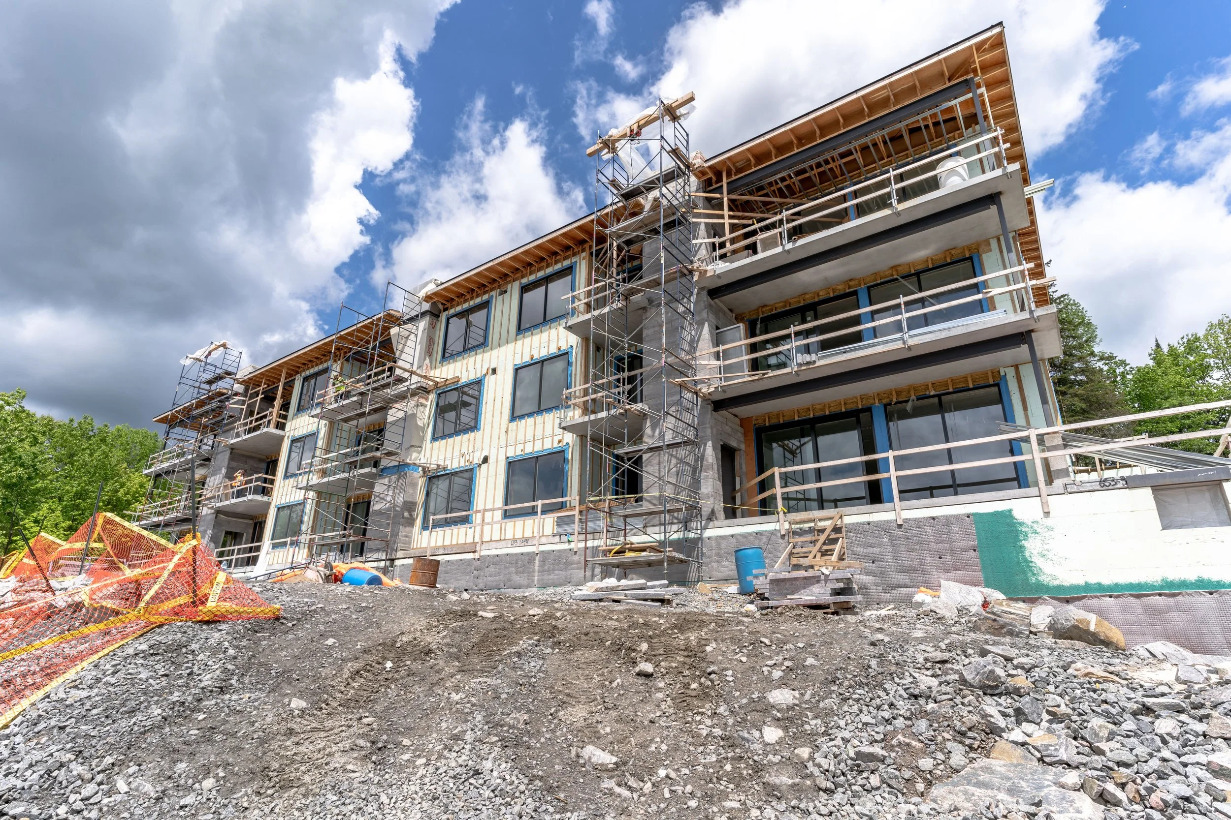 Under-construction multi-story building with scaffolding, ICF product and exposed framework, set against a partly cloudy sky.