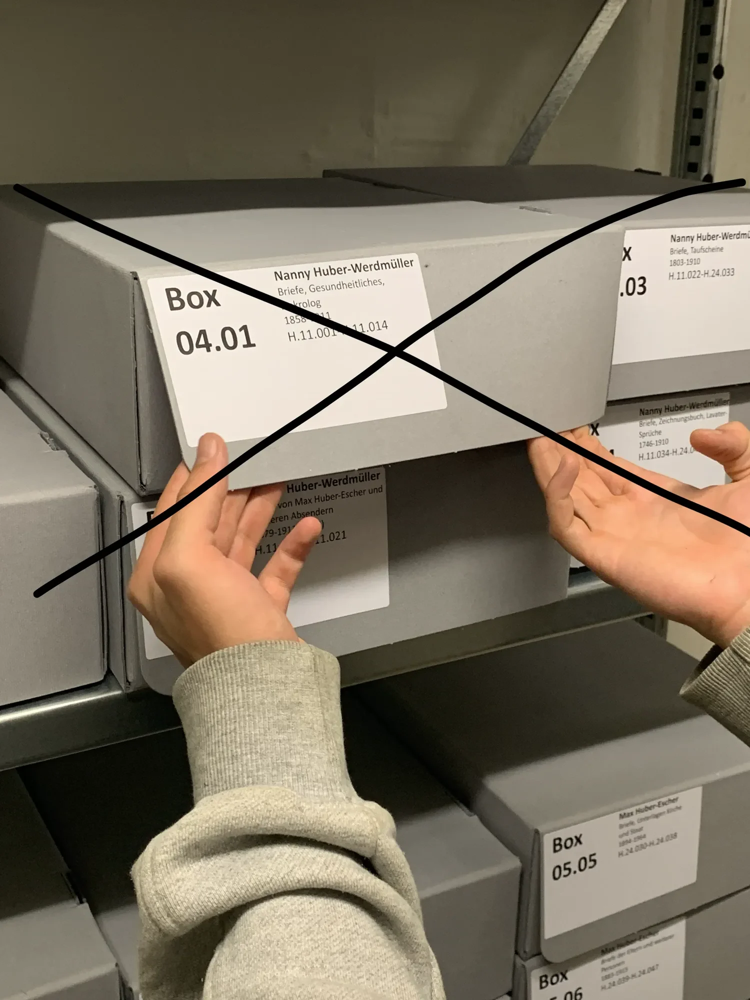 Negative example with a black cross: Hands are pulling a labeled archive box sideways off the shelf without supporting the bottom.
