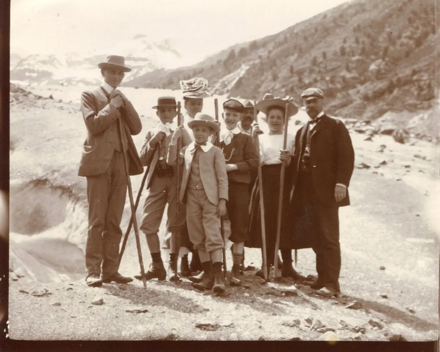 Black-and-white photograph of a family with a mountain guide in the Morteratsch region in the canton of Graubünden, Switzerland, in June 1907. Everyone is carrying a long walking stick.