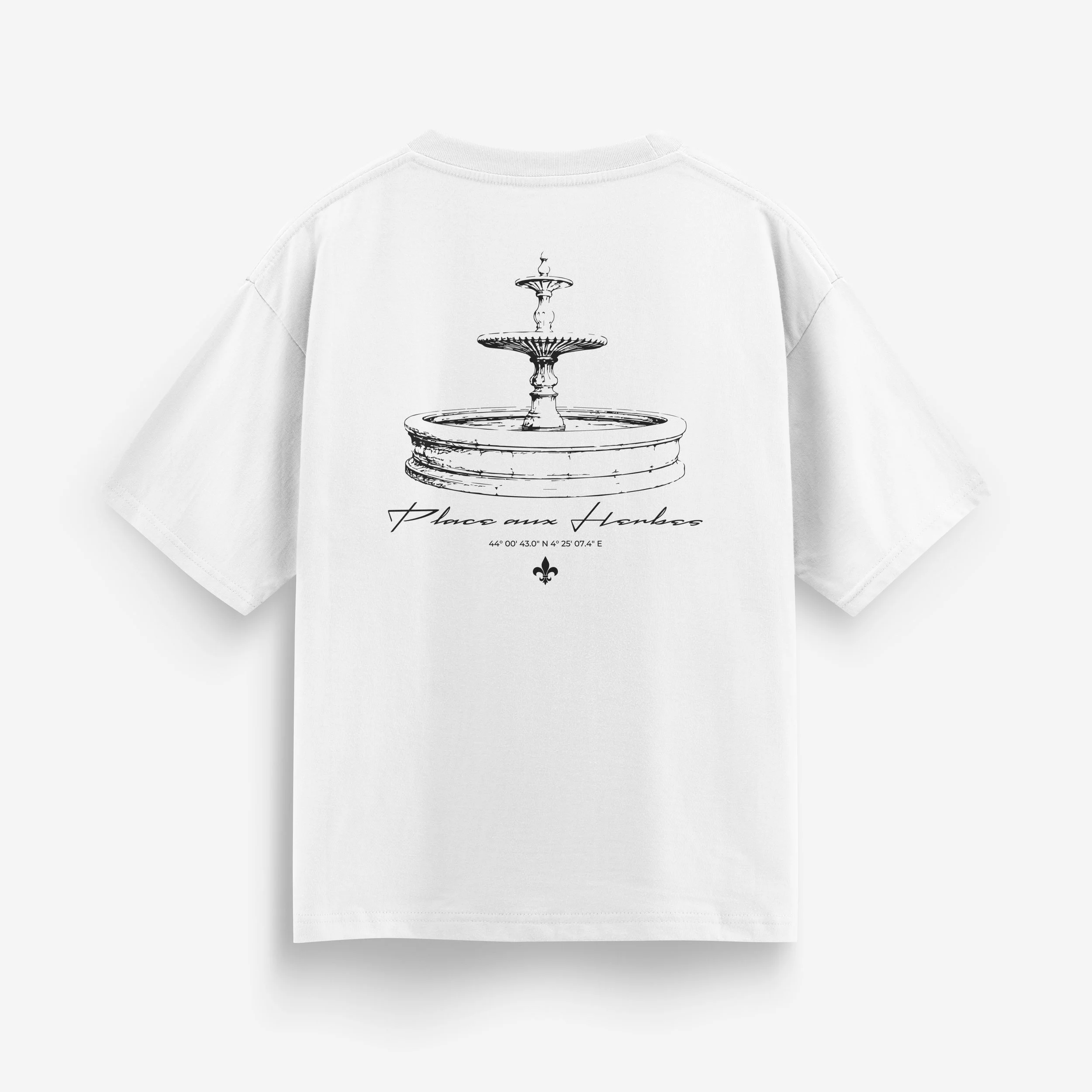 T-shirt blanc avec une illustration d'une fontaine à deux niveaux et des inscriptions en français 'Place aux Herbes', coordonnées GPS 44°00'43.0" N 4°25'07.4" E, et un symbole de fleur de lys en bas.