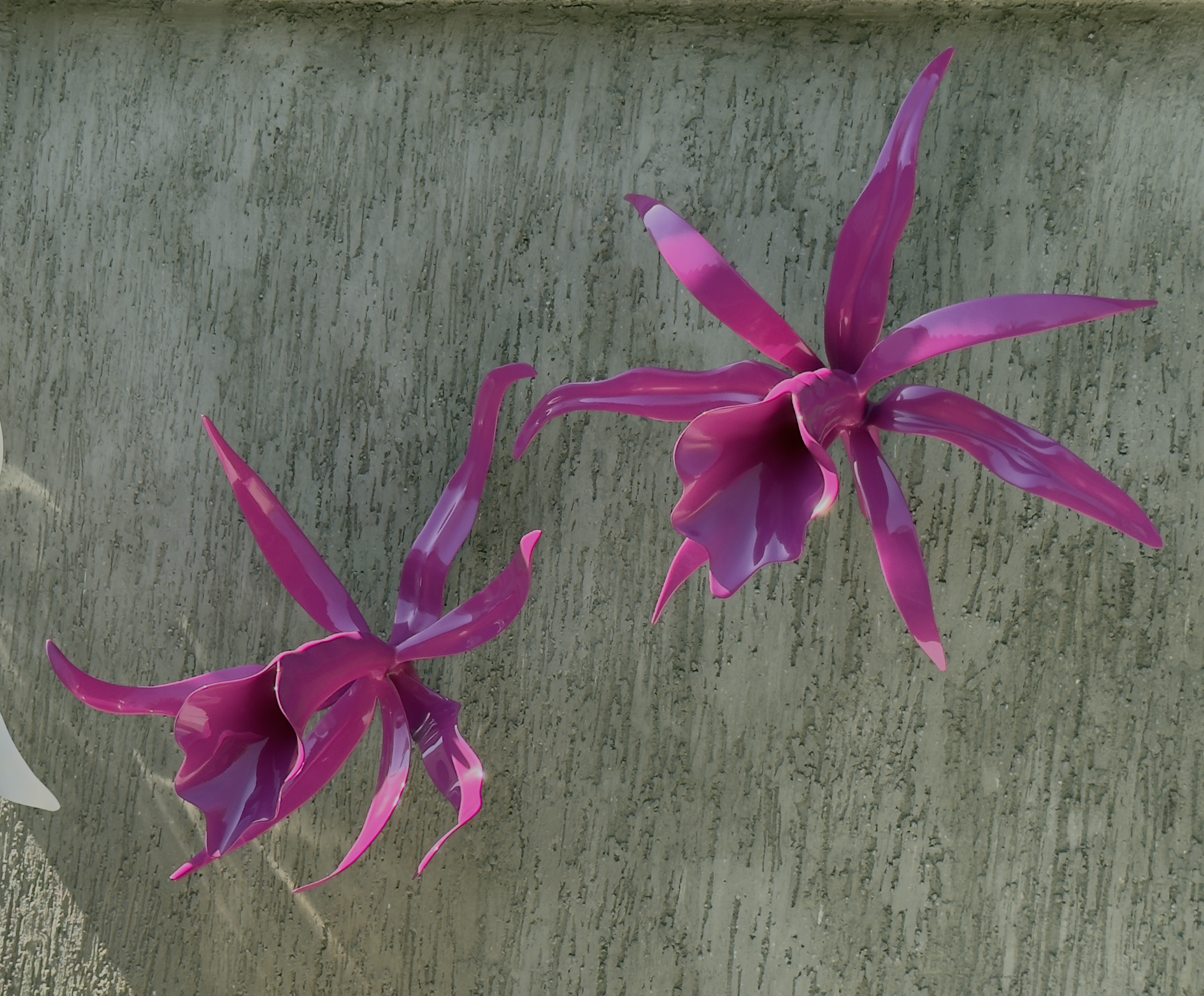 Pink and purple glass art sculpture resembling a floral design placed on a concrete surface.