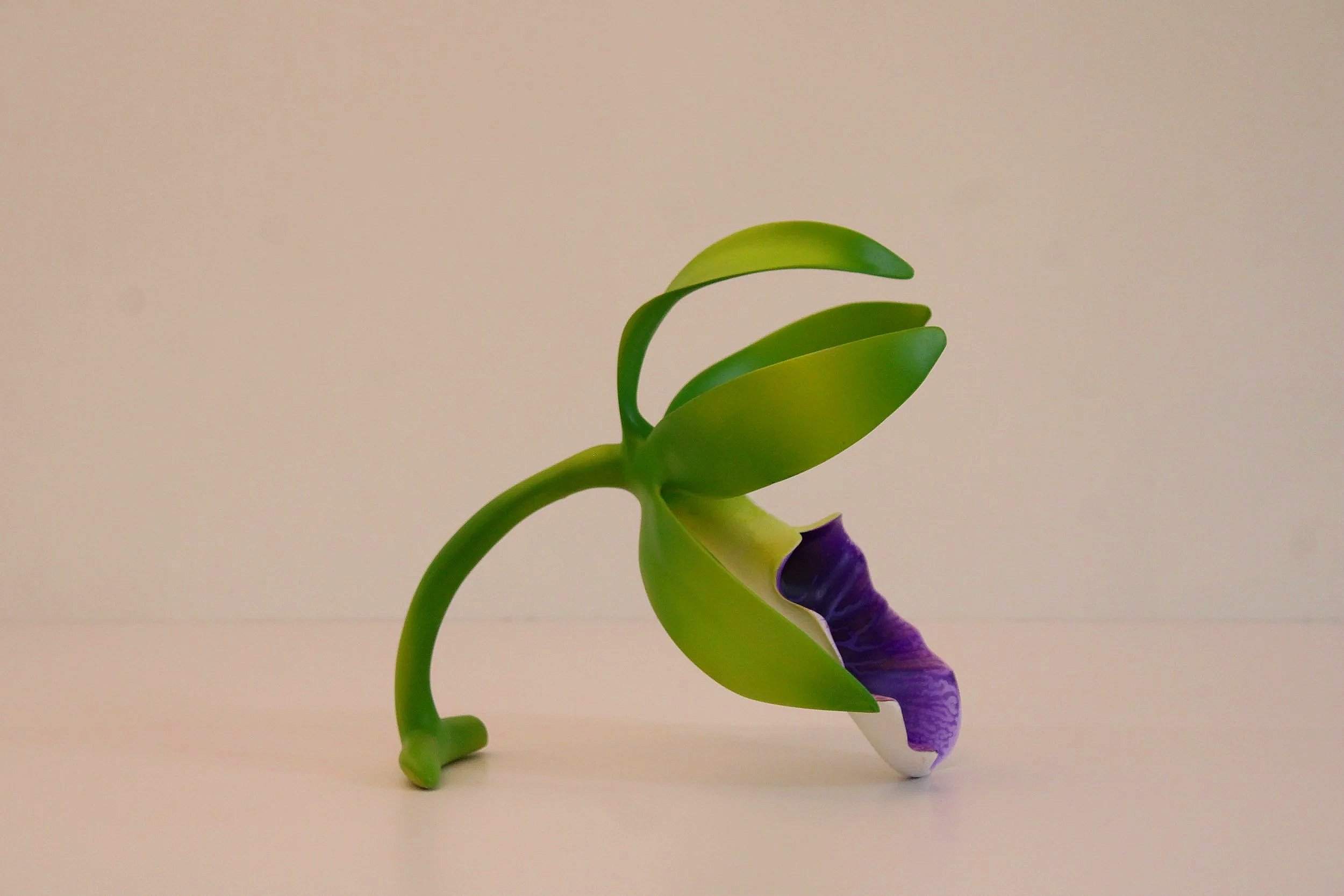 A colorful plastic toy figure of a character with a purple and white outfit and green appendages, in a partial profile view against a plain background.