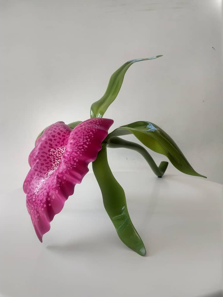 Decorative artificial pink and green flower with a curved green stem and leaves on a white surface.