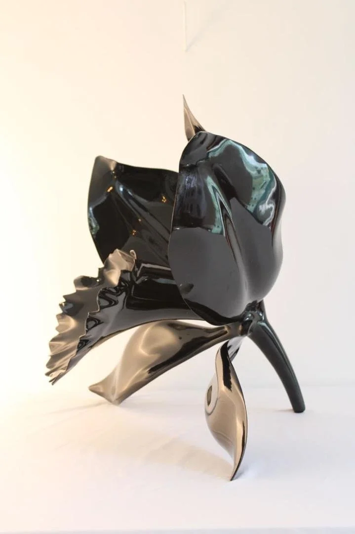 Abstract sculpture resembling a stylized rose with black, metallic, and reflective surfaces.