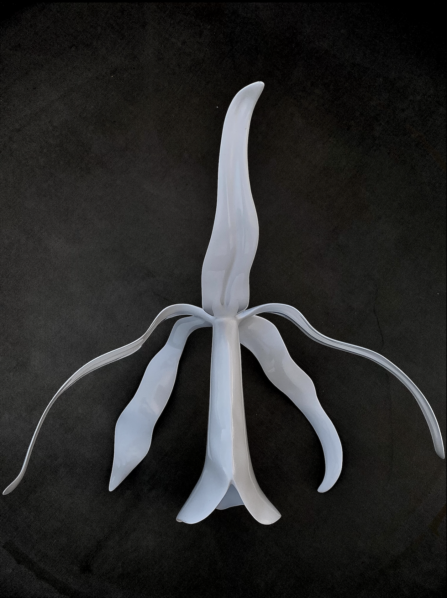 A white decorative plastic stand with multiple curved legs, placed on a black surface.