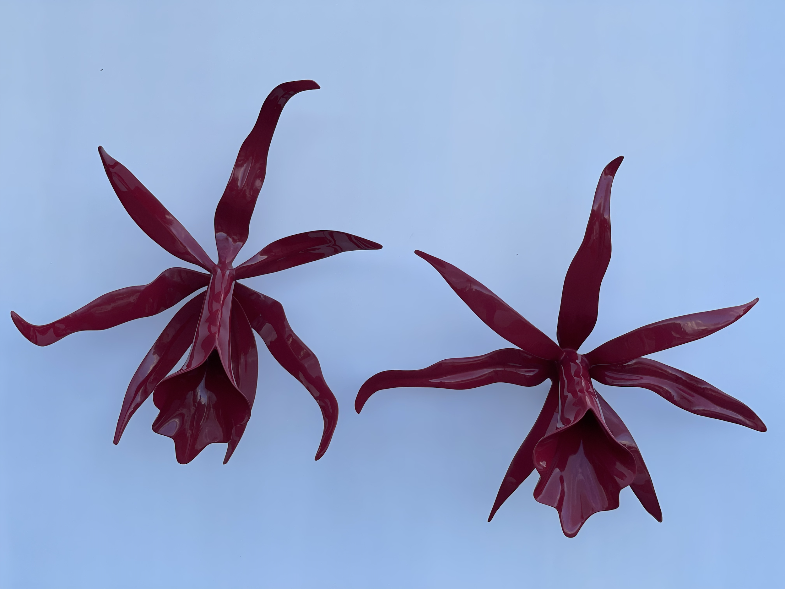 Close-up of red glass or plastic leaves against a blue sky background.