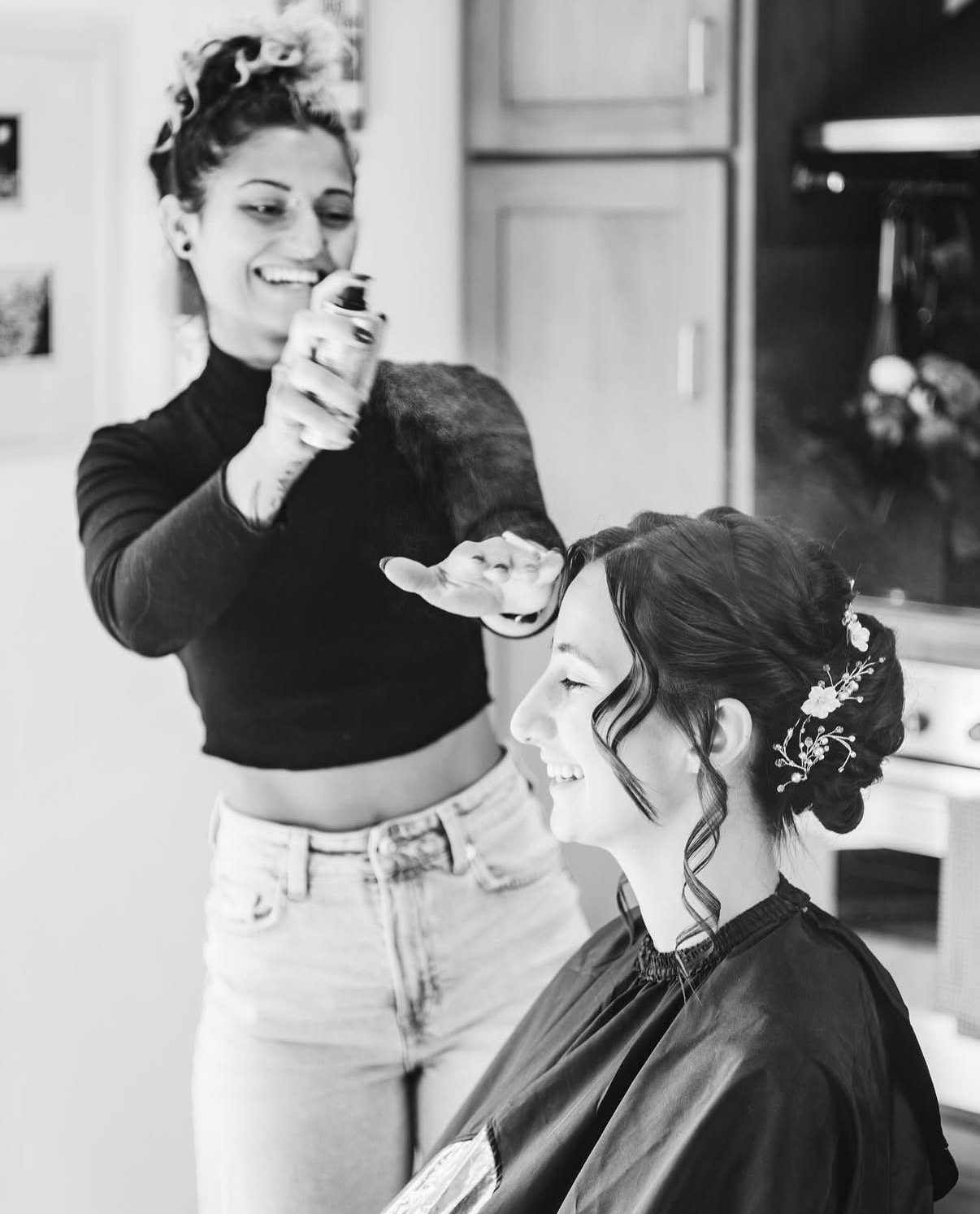 Bridal hairstylist creating an elegant wedding updo with floral hair accessories