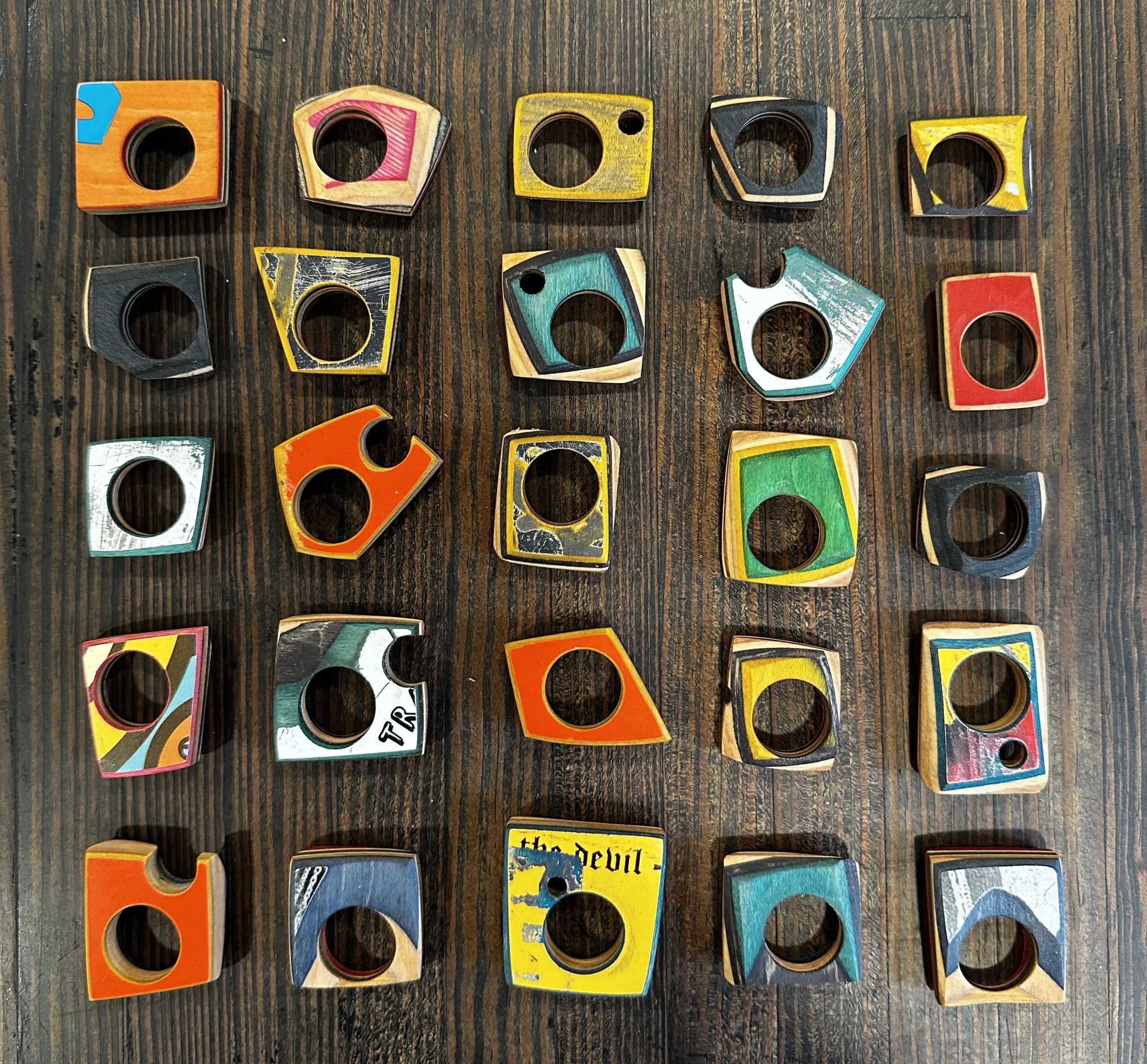 Handmade rings cut and shaped from recycled skateboard decks, in various color tones, by George Peterson.