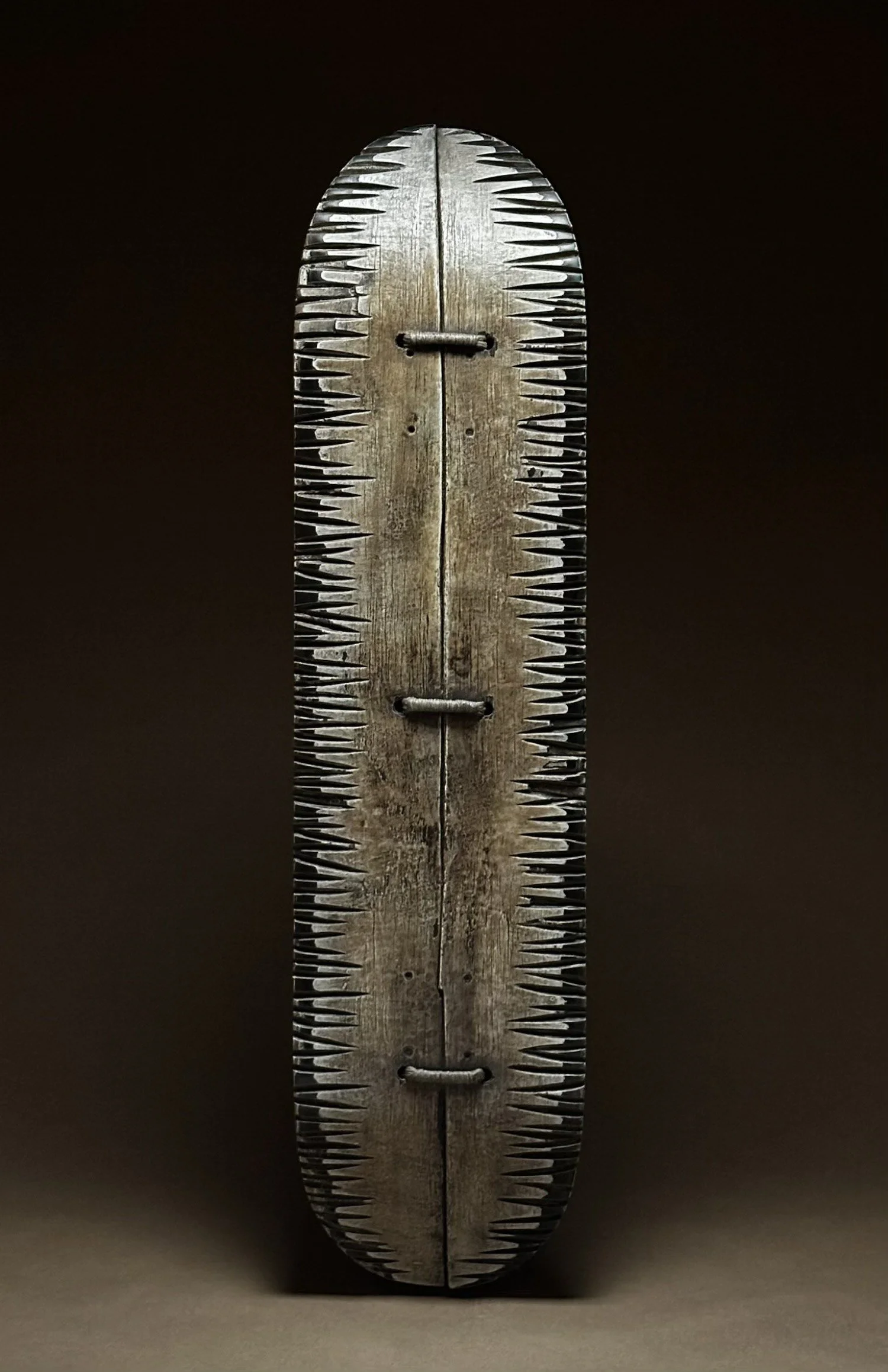 Full view of LINGO Stitched Edges, a wall sculpture with three large hand stitches and textured edges on a reclaimed skateboard deck.