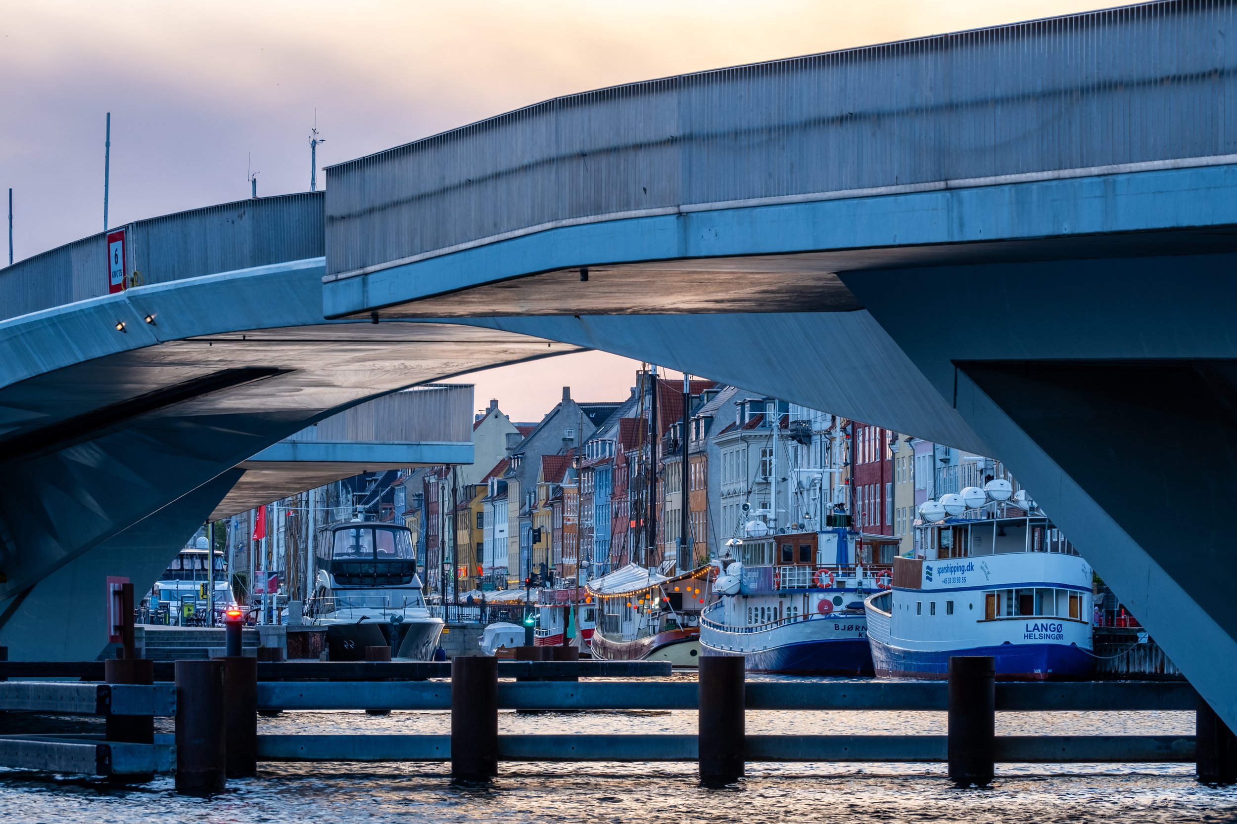 Nyhavn set under inderhavnsbroen/kyssebroen. Aftenlys. København.