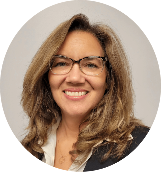 Headshot of a woman with shoulder-length wavy hair, wearing glasses, smiling, in a professional setting.