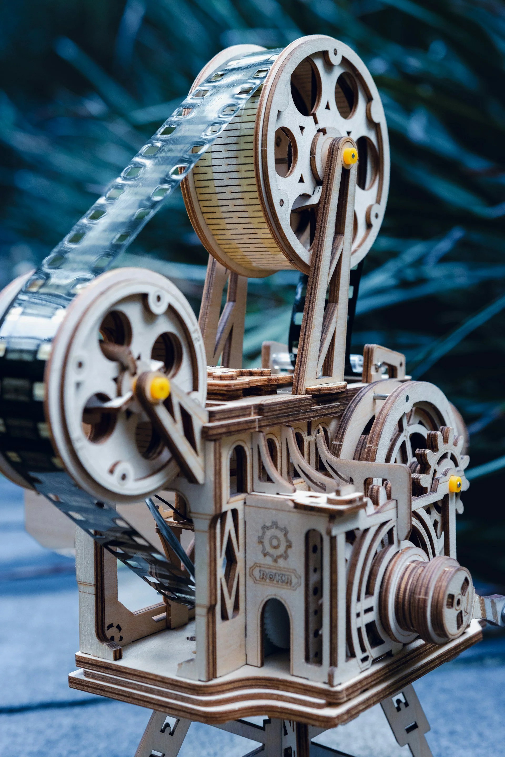 A detailed wooden model of a vintage steam locomotive with intricate gears and components on display outdoors.