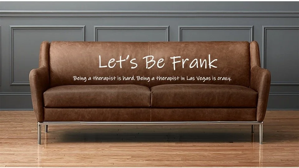 A brown leather sofa with a message written on it that reads "Let's Be Frank" and a subtitle "Being a therapist is hard. Being a therapist in Las Vegas is crazy." The sofa is against a gray wall with decorative paneling, on a wooden floor.
