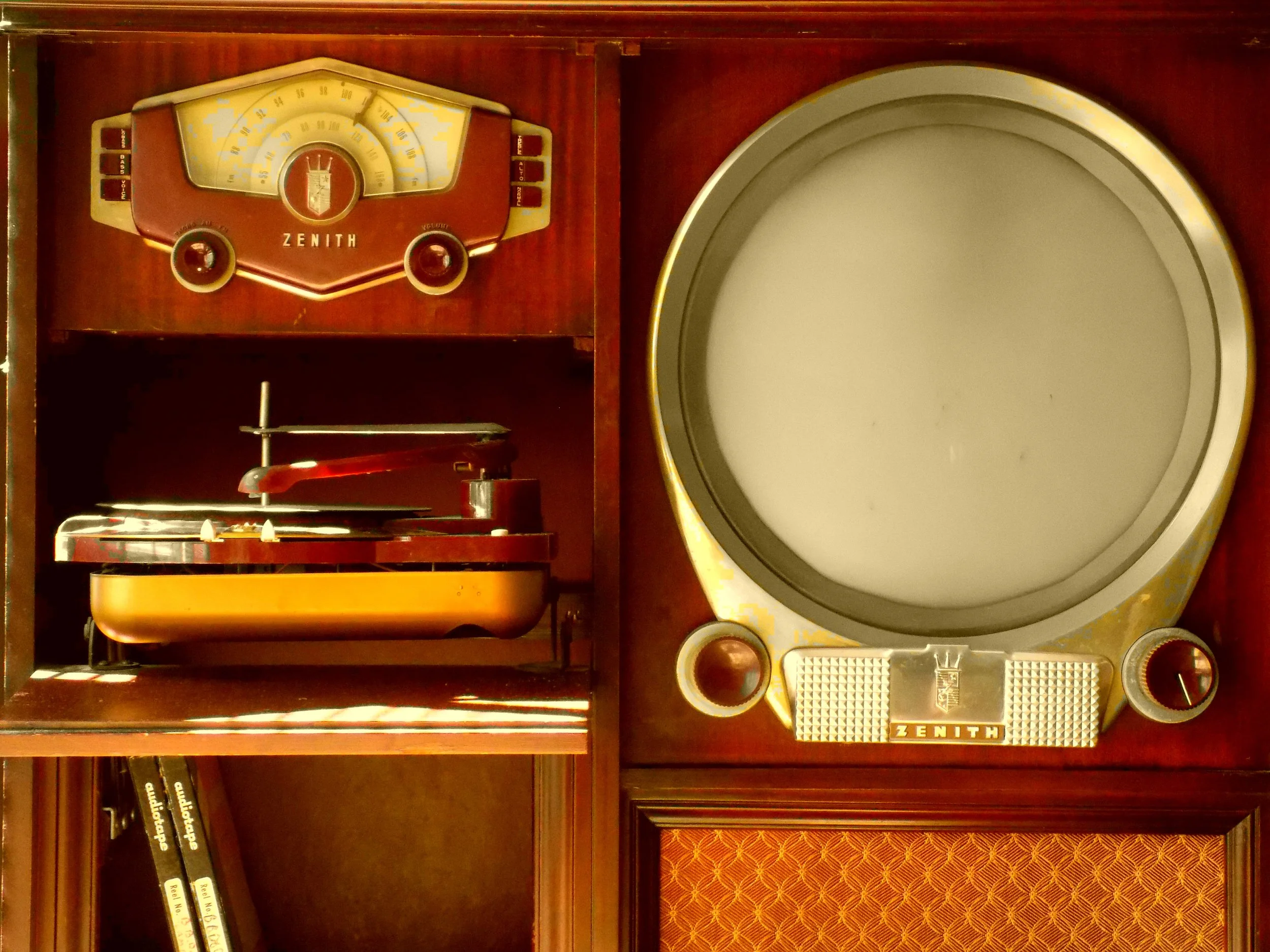 Vintage Zenith radio and turntable on wooden bookshelf with books and decorative items.