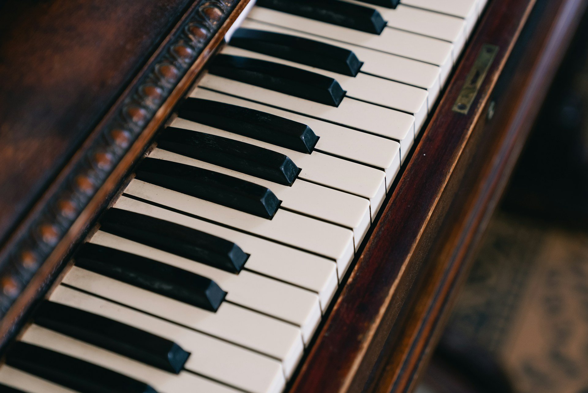 Close-up of a vintage piano keyboard showing black and white keys with a wooden piano frame.