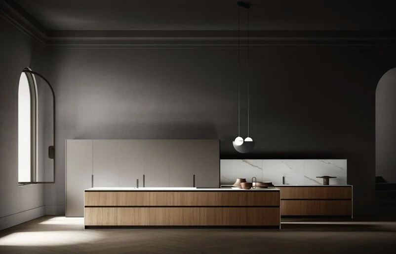 Cucina moderna con mobili in legno e pareti grigie, illuminata dalla luce naturale da una finestra e una luce artificiale sospesa.