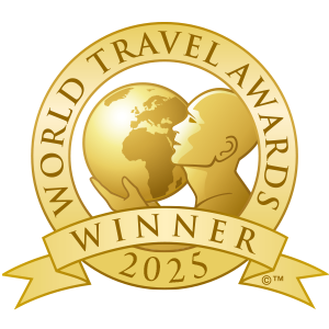 Gold-colored emblem with a globe and a woman's face in profile, surrounded by the words 'World Travel Awards Winner 2025' on a ribbon.