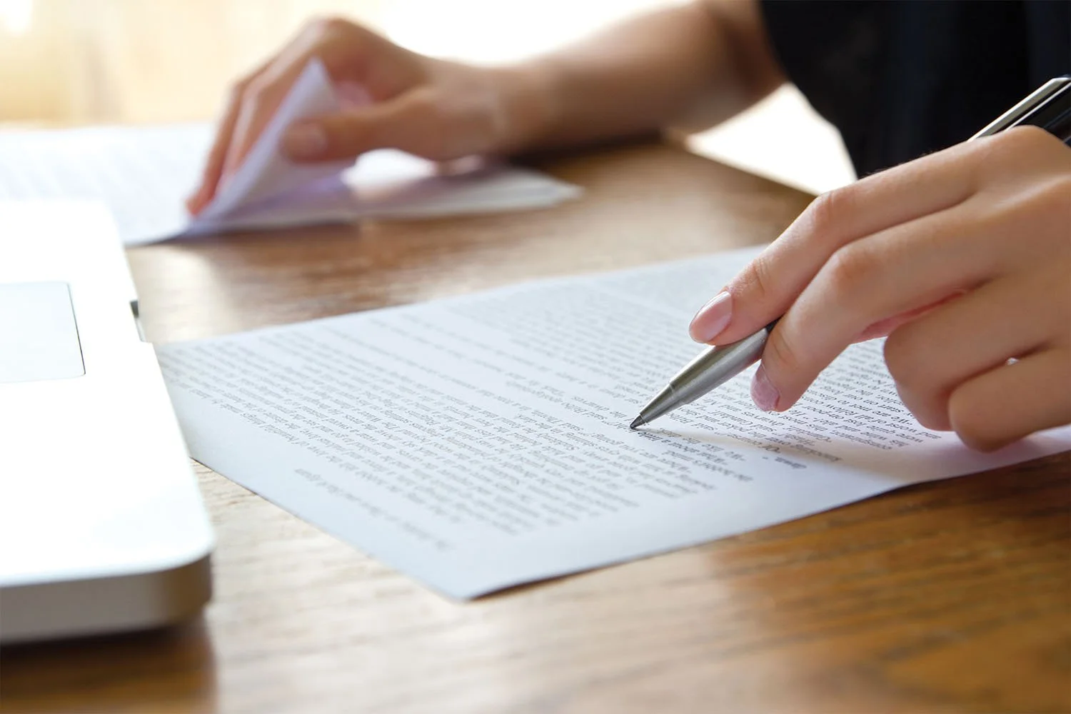 A close-up view of a person writing on a sheet of paper with a pen.