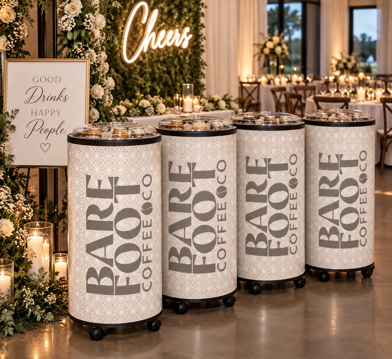 Four cylindrical coffee dispensers labeled 'BARK COFFEE' in a decorated event space with floral arrangements, candles, and a sign that reads 'Good Drinks Happy People'.