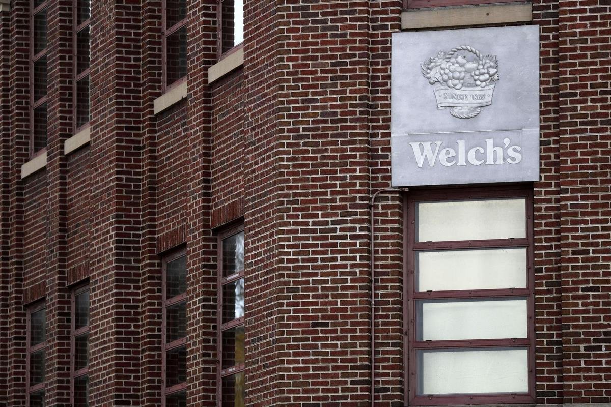 Close-up of a brick building with a Metal sign for Welch's fruit products mounted on the exterior wall.