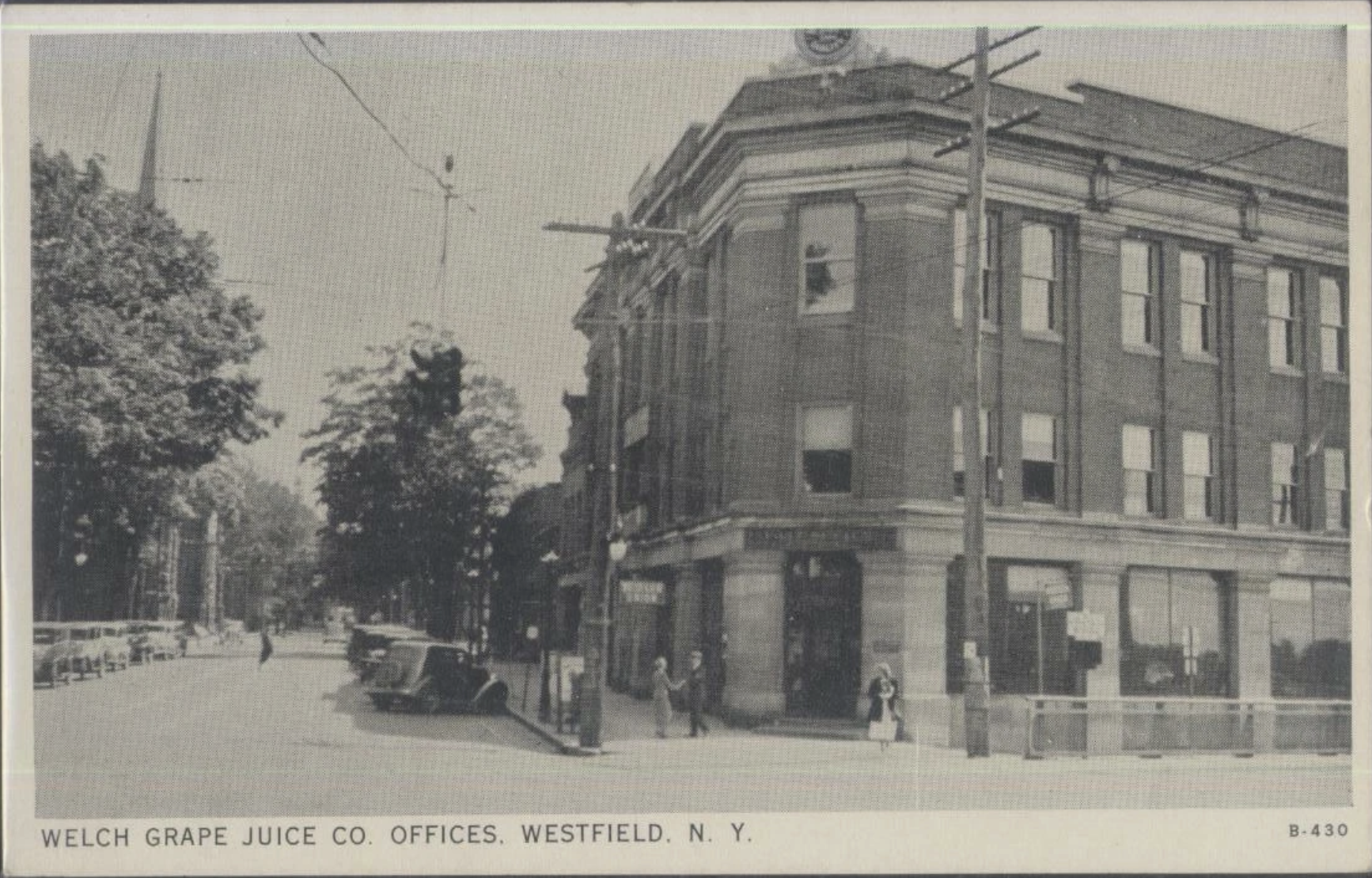 Black and white photo of the Welch Grape Juice Co. offices building on Westfield Avenue in North Westfield, New York, with street view, trees, cars, and pedestrians.