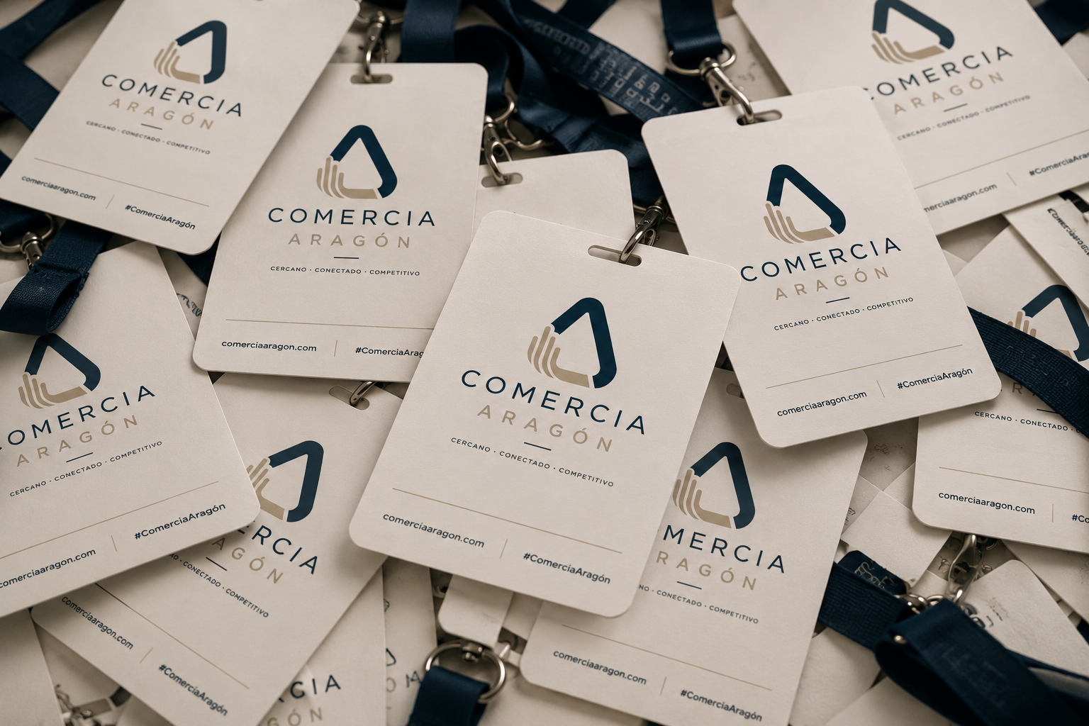 Tarjetas de identificación con el logo de Comercio Aragón, apiladas y colgadas con cordones azules.