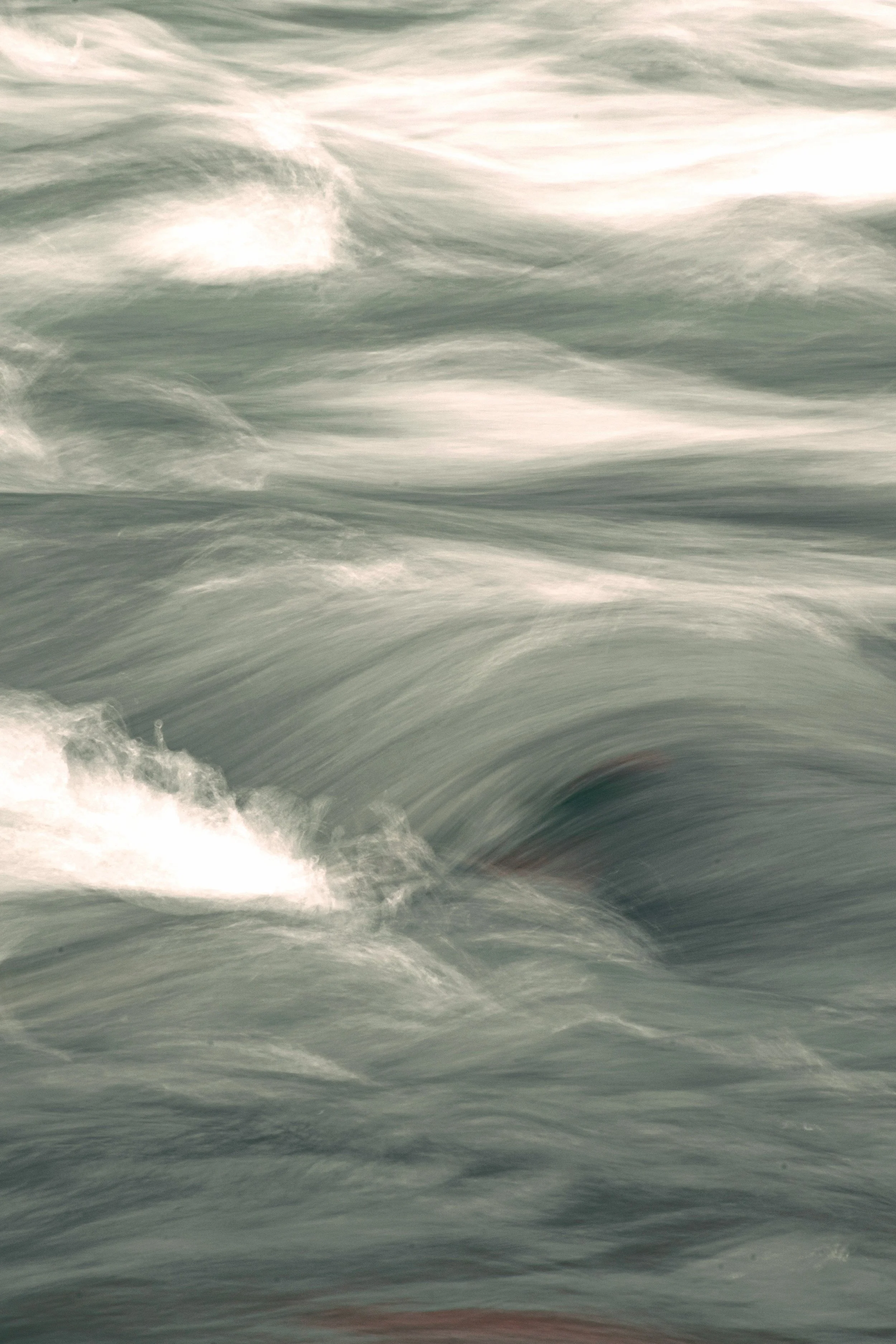 Een close-up van golven op zee met wit schuim en een groene-grauwe tint.